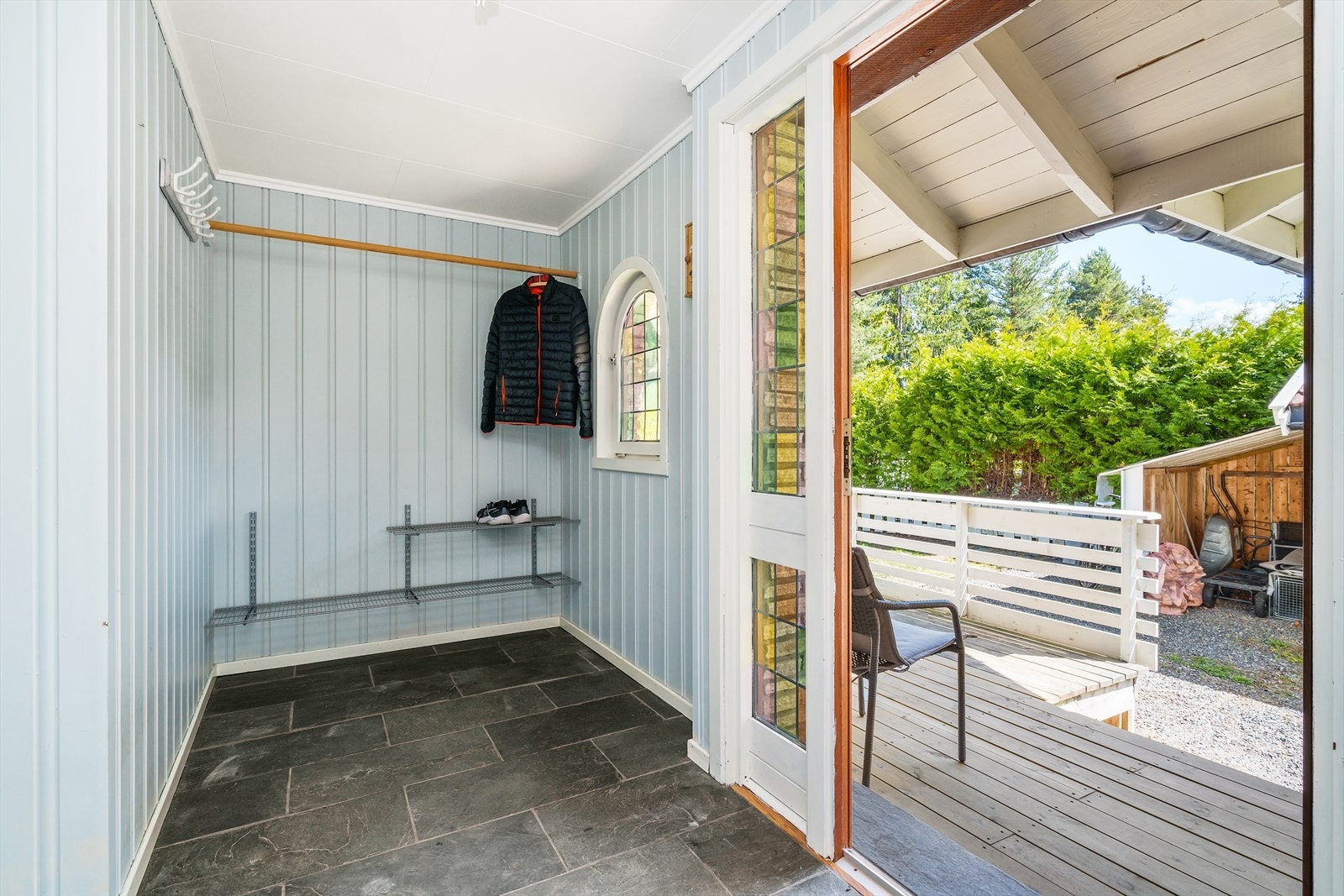 Velkommen inn til en romslig entrè med flislagt gulv og malt panel på vegg. Galleribilde