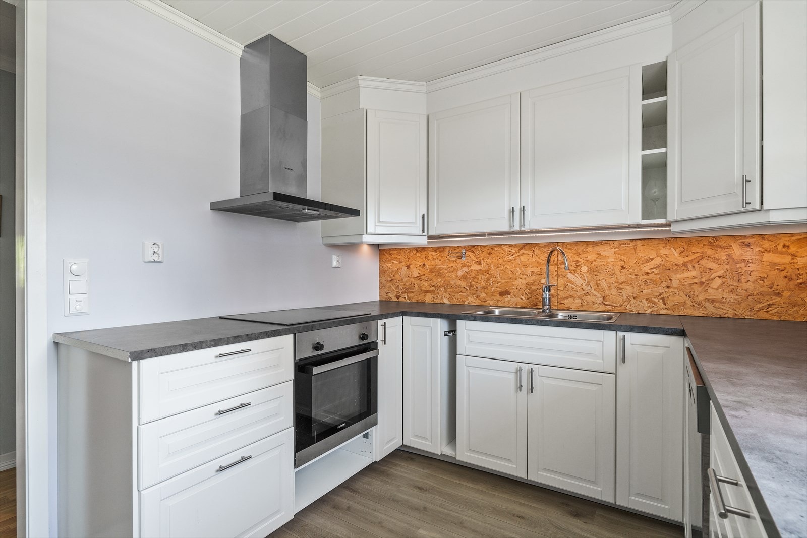 Eldre og klassisk kjøkkeninnredning med profilerte fronter og benkeplate av laminat. Galleribilde