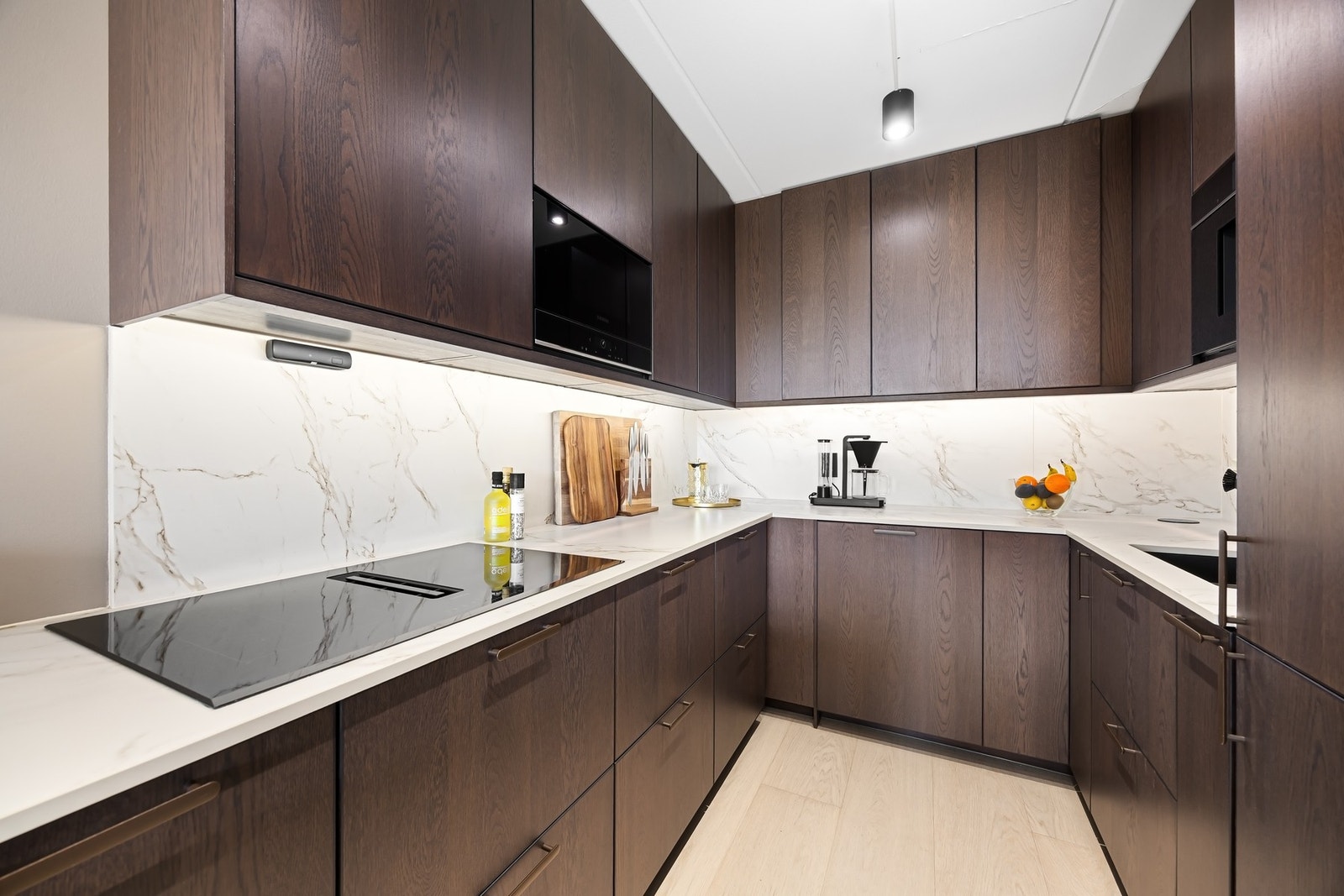 Stekeovn, mikrobølgenovn, 80 cm induksjonstopp, oppvaskmaskin, kaffemaskin, kjøl og frys er integrert i innredningen. Galleribilde