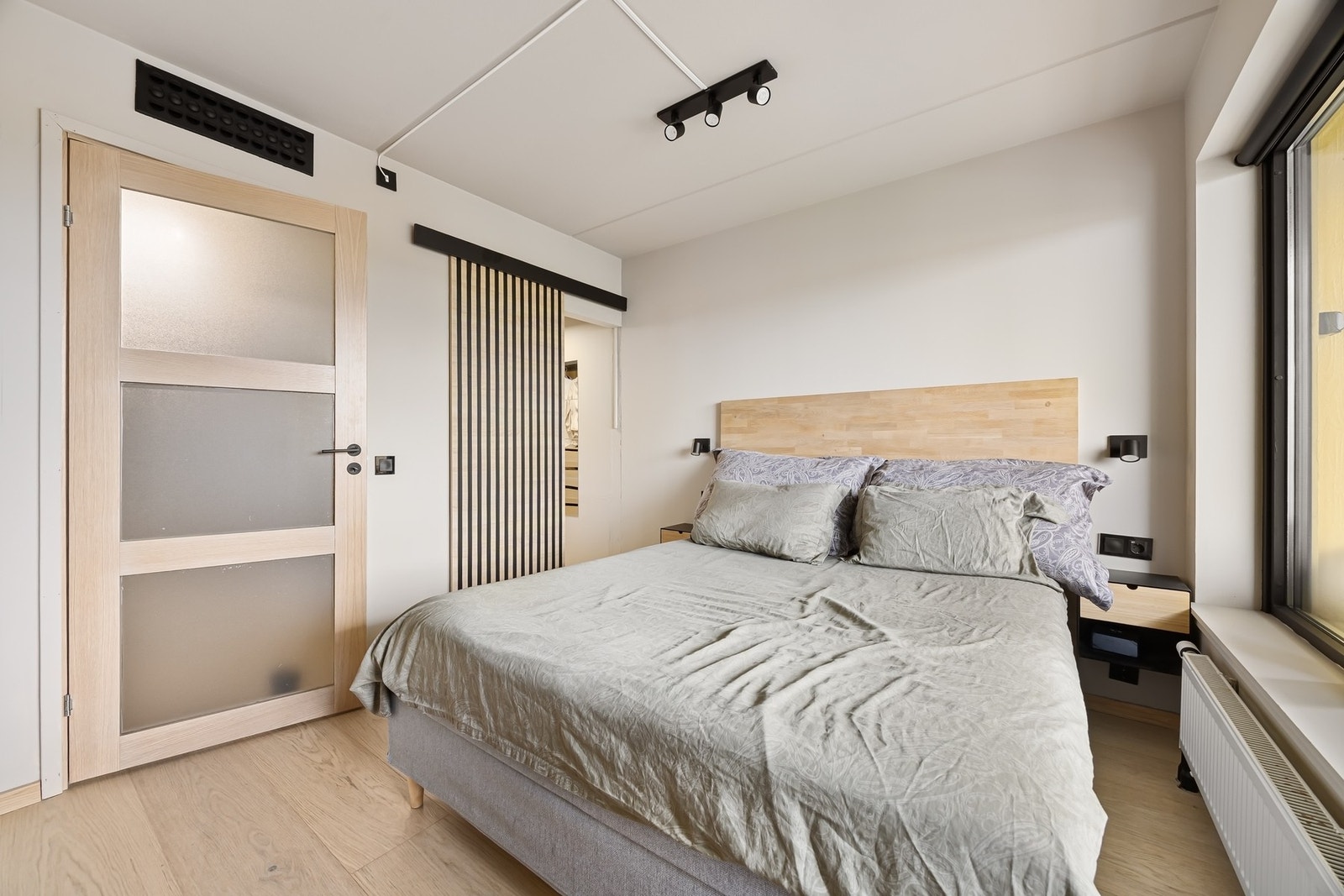 Walk-in closet adsiklt fra soverommet med en lekker skyvedør av spiler. Galleribilde