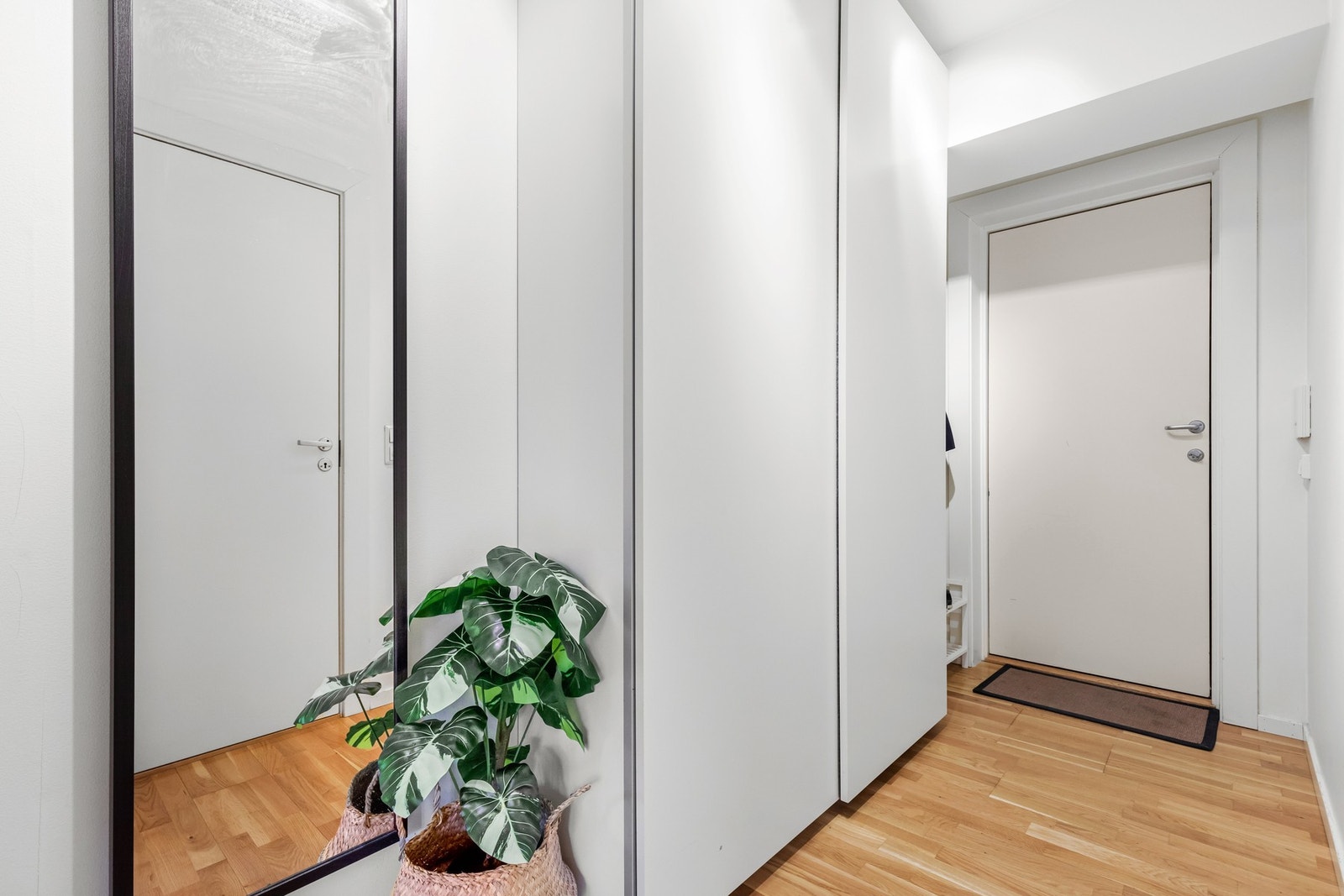 Inn døren til en lys og innbydende entré med 3-stavs parkett og glatte malte veggflater Galleribilde