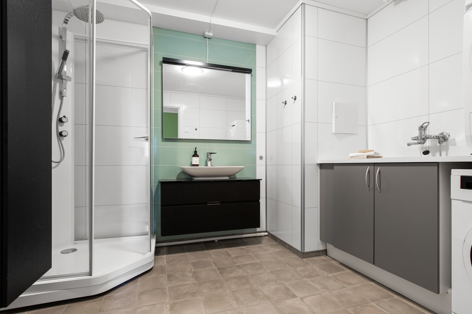 Bad/vaskerommet i underetasjen ble oppgradert i 2016 og har hvite våtromsplater med flisimitasjon på veggene, grå fliser med gulvvarme, sort servantinnredning med speil, mekanisk avtrekk, dusjkabinett med regnfallsdusj og opplegg for vaskemaskin. Galleribilde