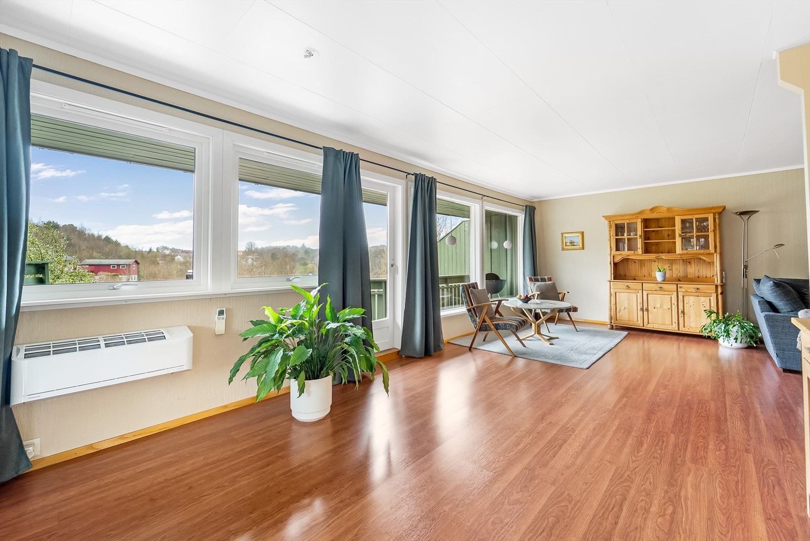 Lys og romslig stue med store vinduer som gir godt med lysinnslipp. Varmepumpe på vegg. Galleribilde