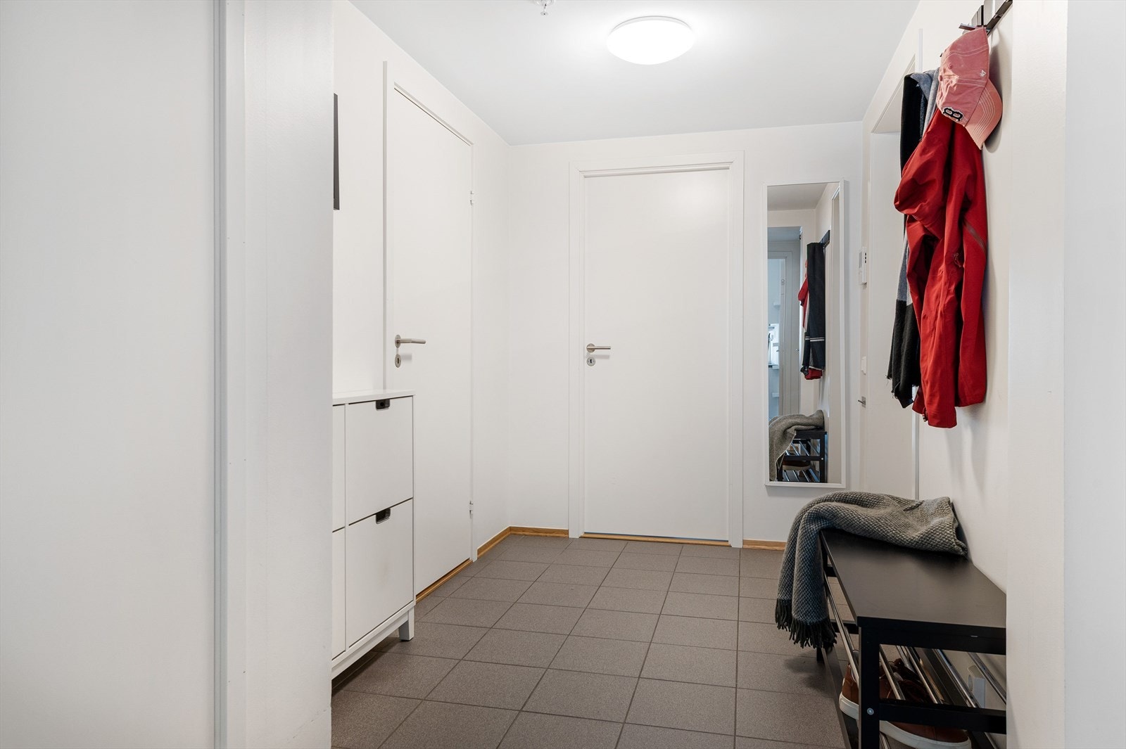 Flislagt gang med plass til garderobe og lagring av sko- og yttertøy Galleribilde