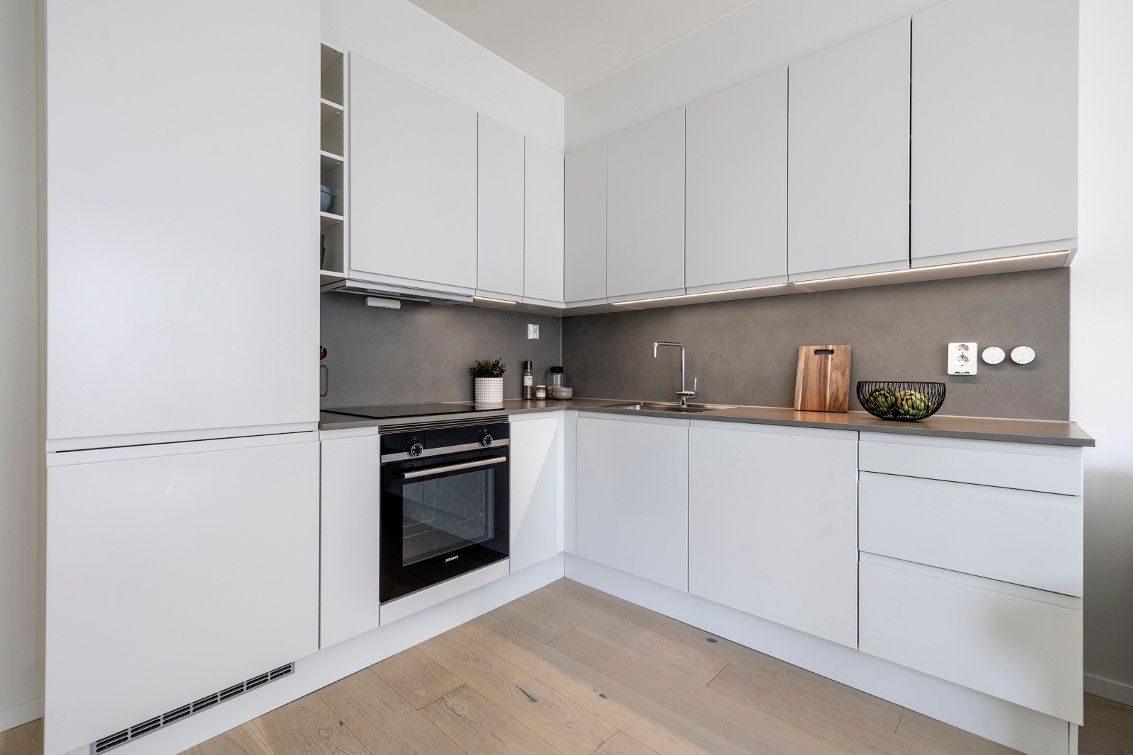 De hvite, glatte frontene og den grå laminert benkeplaten med nedfelt oppvaskkum gir et eksklusivt preg Galleribilde