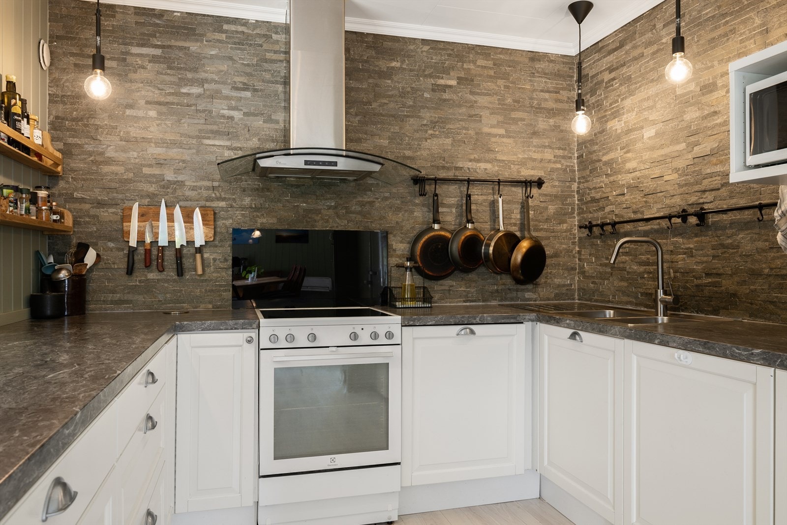 Kjøkkenviften i stål står fint til benkeplaten og den grå veggen. Galleribilde