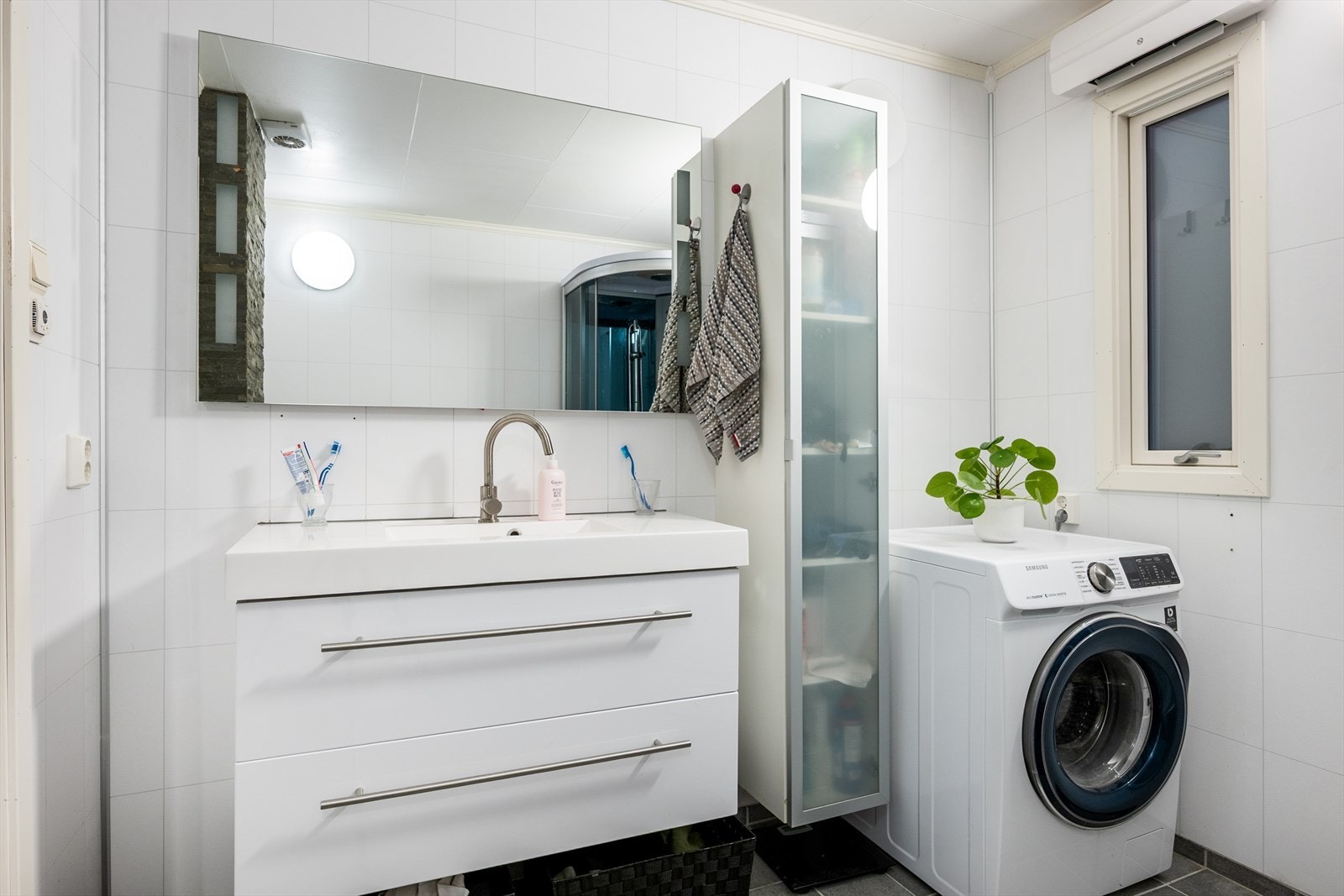 Rommet er innredet m/lys skuffeinnredning og speil, høyskap, vegghengt wc og dusjkabinett. I tillegg opplegg for vaskemaskin. Galleribilde