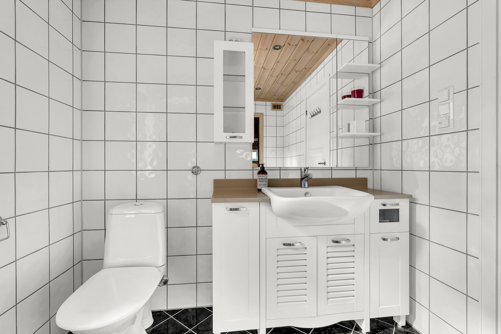 Badet er utstyrt med toalett, servant med innredning og dusjkabinett. Galleribilde