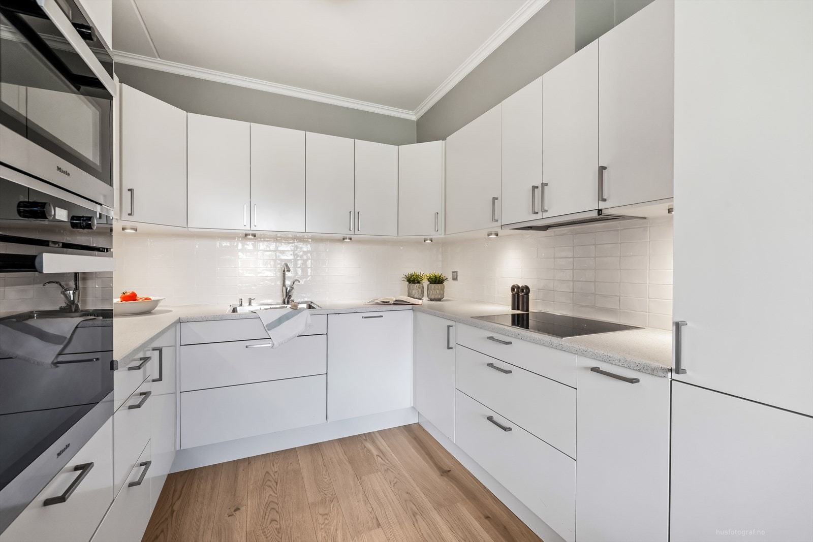 Klassisk og elegant kjøkkeninnredning med hvite slette fronter og benkeplate av laminat. Galleribilde