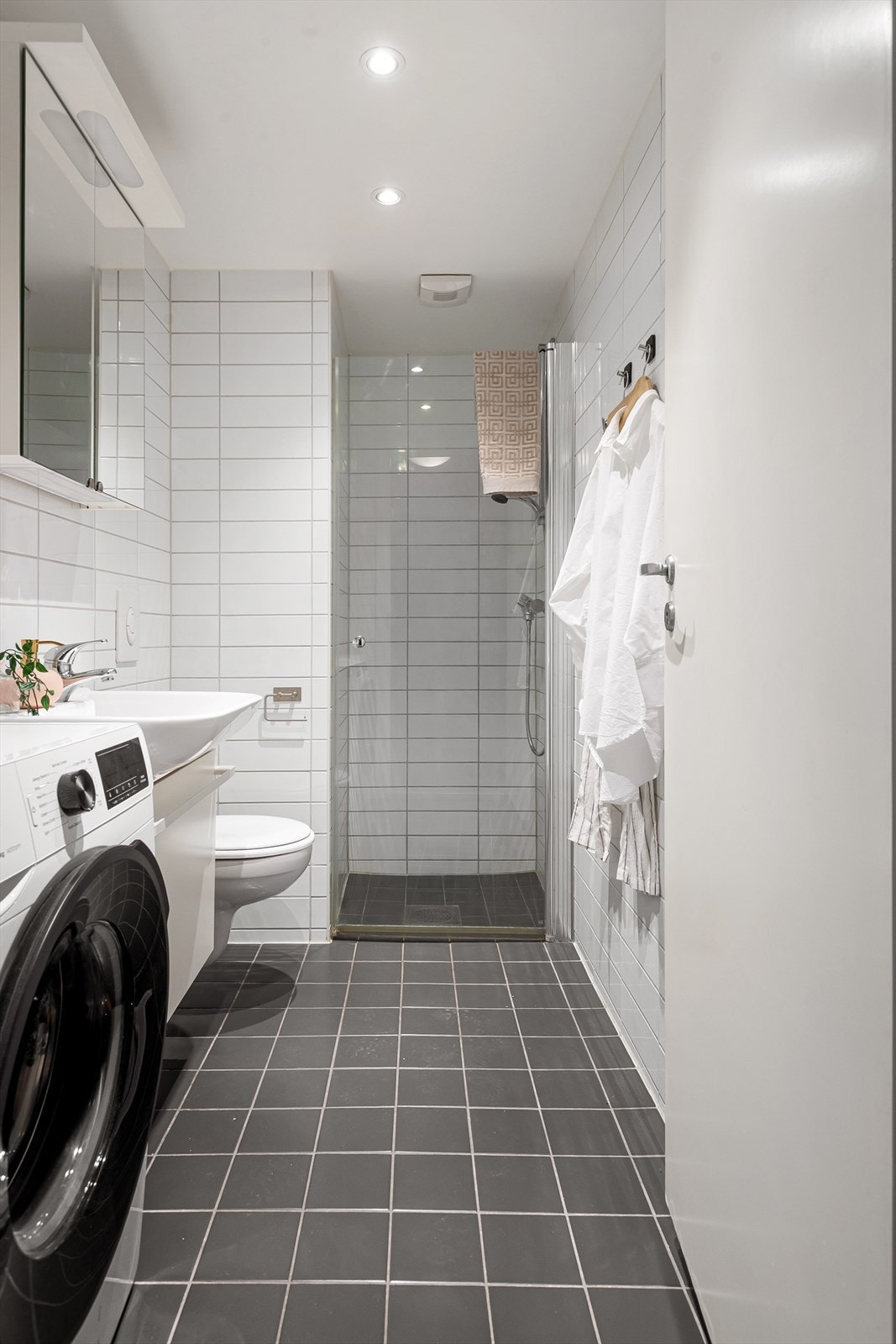 Lyst bad med plass til vaskemaskin og praktisk innredning for hverdagskomfort. Galleribilde