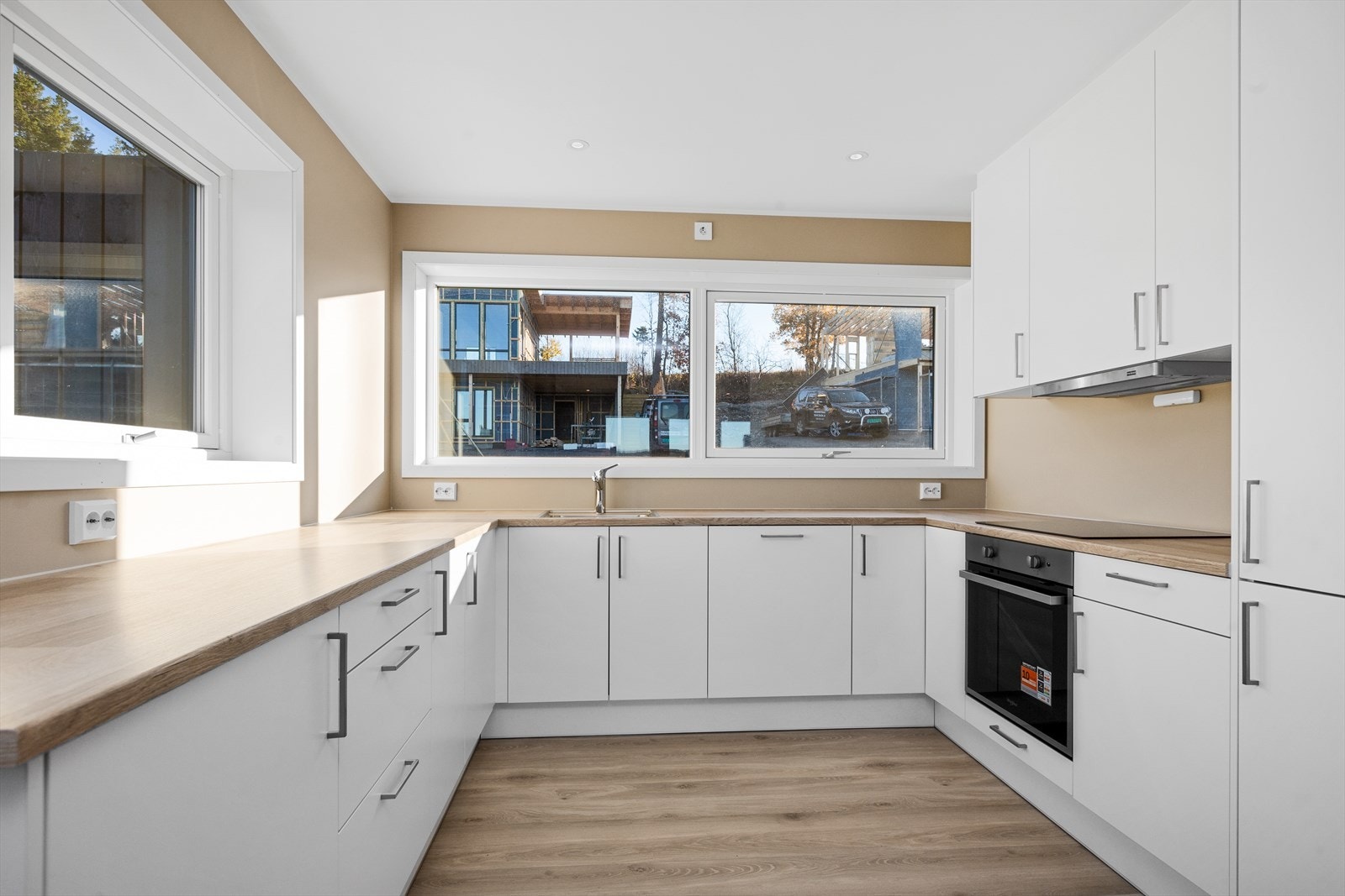 Kjøkkeninnredning fra Mesterkjøkken, type Soft, malt med laminat benkeplate og integrerte hvitevarer fra Whirlpool (komfyr, induksjon platetopp, ventilator, oppvaskmaskin og kombinert kjøle/fryseskap). Elektronisk lekkasjestoppventil og komfyrvakt Galleribilde