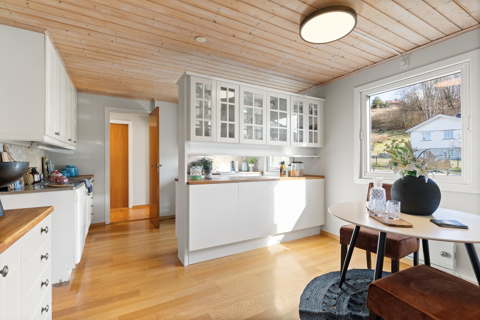Kjøkkeninnredning med profilerte fronter, fliser på vegg over benkeskap, belysning under overskap og enkelte overskap med glassfronter. Heltre benkeplate, benkebeslag i rustfritt stål med utslagskum og kum. Galleribilde
