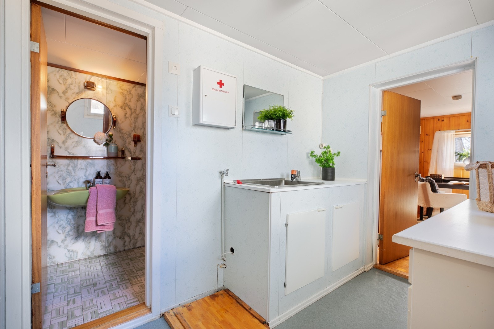 Vaskerom med gulvbelegg på gulv og baderomsplater på vegger. Vaskeromsinnredning med glatte fronter. Opplegg for vaskemaskin og skyllekum i rustfritt stål. Galleribilde