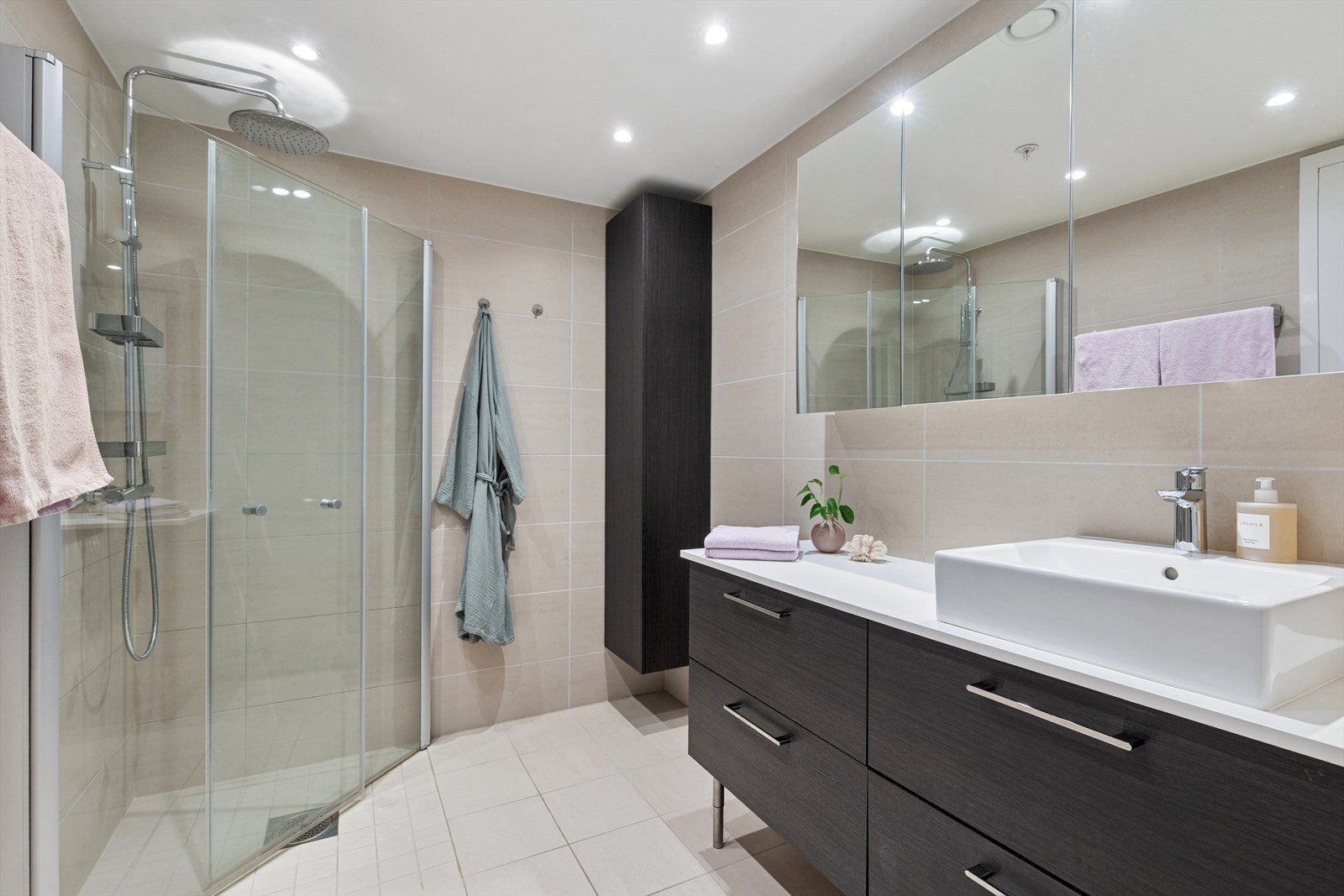 Delikat baderom med store sandfargede fliser og pen innredningen. Galleribilde