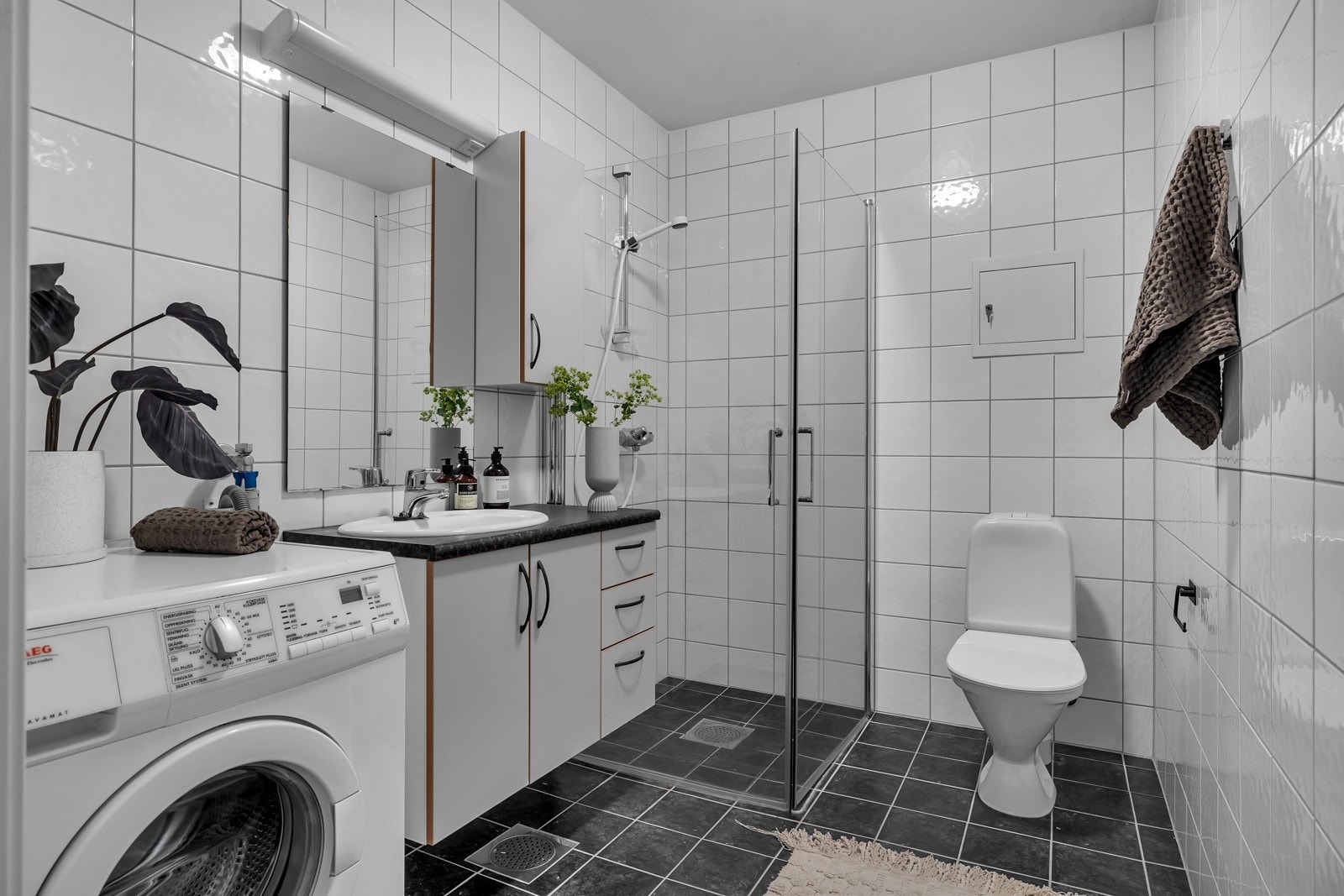 Flislagt bad med dusjhjørne, wc, servant med under og overskap samt opplegg til vaskemaskin. Galleribilde
