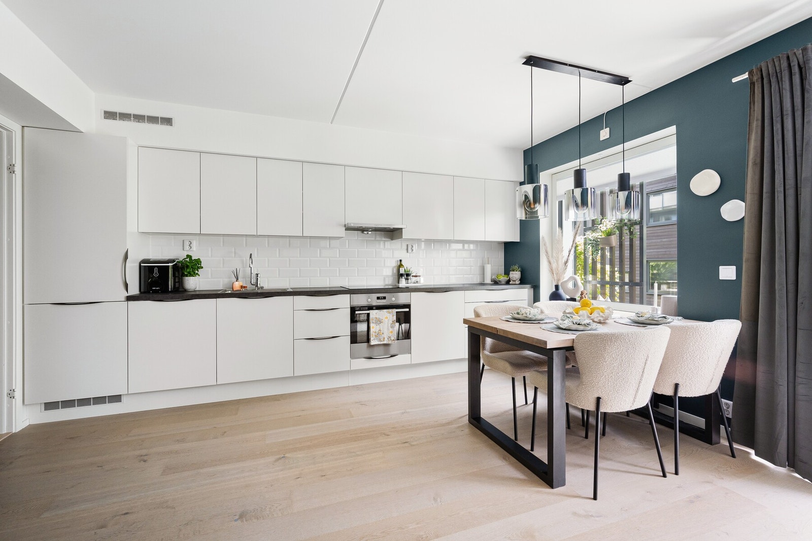 Kjøkkenet har et moderne og stilrent design med hvite, glatte fronter og integrerte hvitevarer. Galleribilde