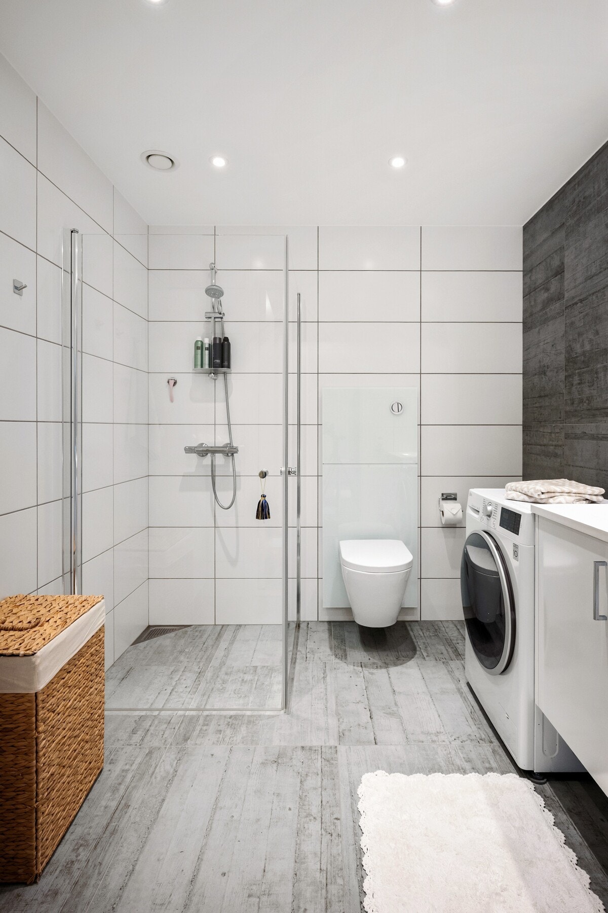 Lekkert og moderne bad med fliser på både gulv og vegger. Badet er utstyrt med dusjhjørne med innfellbare glassdører, vegghengt toalett og servantskap med speil. Galleribilde