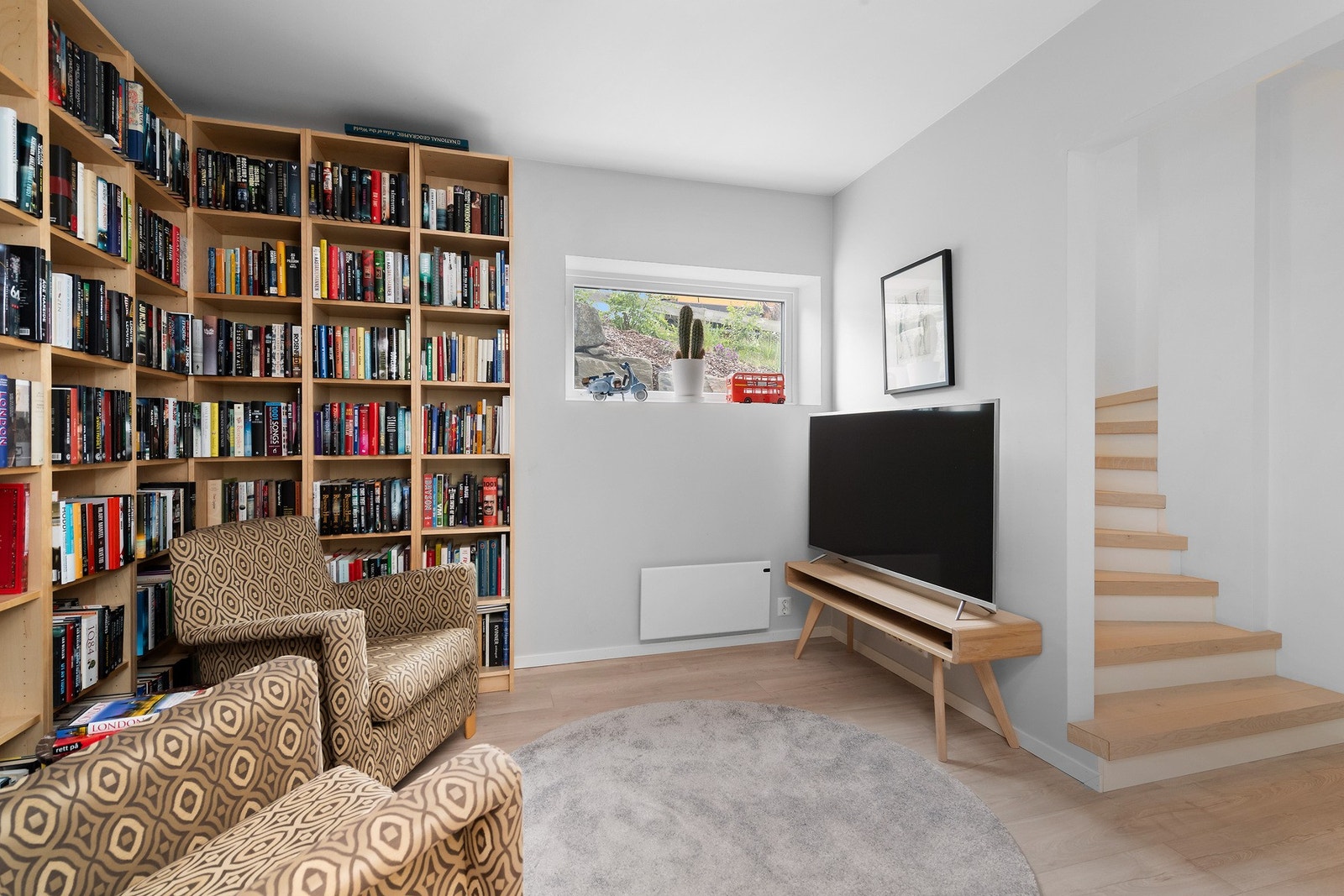 TV-stue/bibliotek i underetasje. Rommet er godkjent som lagringsrom. Det er ikke søkt om bruksendring fra tilleggsdel til hoveddel. Rommet er følgelig ikke godkjent til dagens bruk. Galleribilde