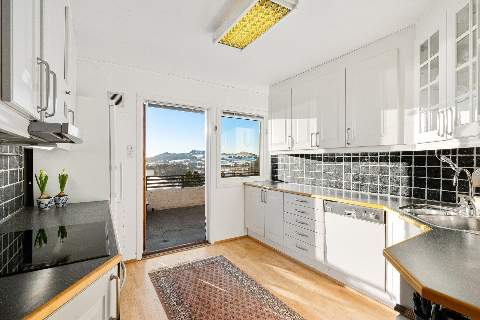 Kjøkkenet ligger tilliggende stuen i andre etasje, med parkettgulv og hvitmalte vegger. En glassdør fører ut til den store terrassen, hvor man kan nyte panoramautsikten. Galleribilde