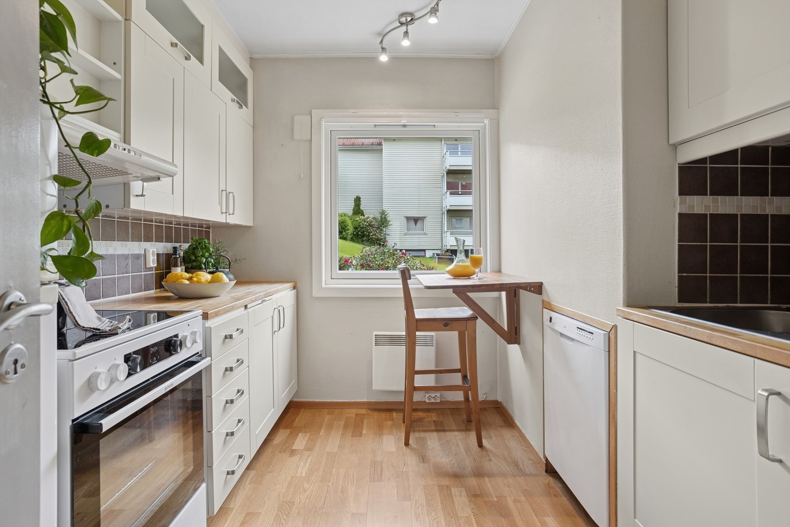 Kjøkkenet har glimrende skap- og benkeplass. Kjøkkeninnredning fra 2008 med hvite fronter, takhøy innredning, heltre benkeplate og keramiske fliser over benkeplaten. Galleribilde