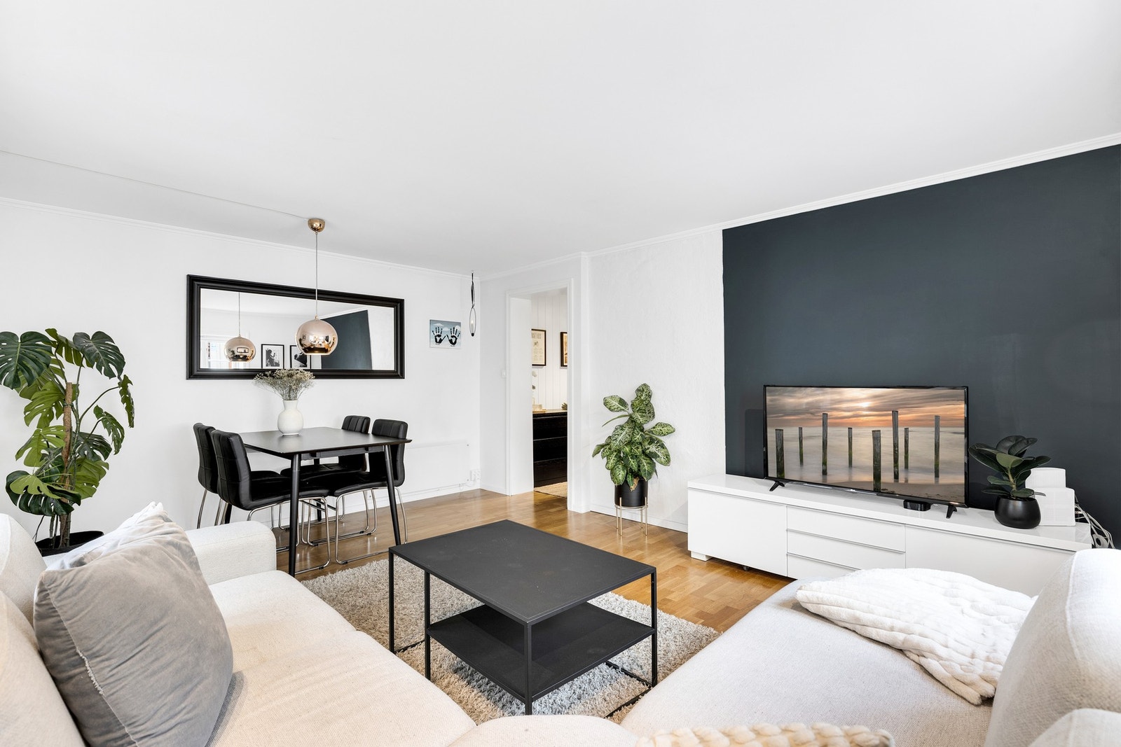 Store møbler i nøytrale toner, mørke kontrastvegger og grønne innslag skaper en lun og elegant atmosfære. Galleribilde