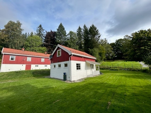 Leiligheten ligger i første etasje av et lite rødt hus Galleribilde