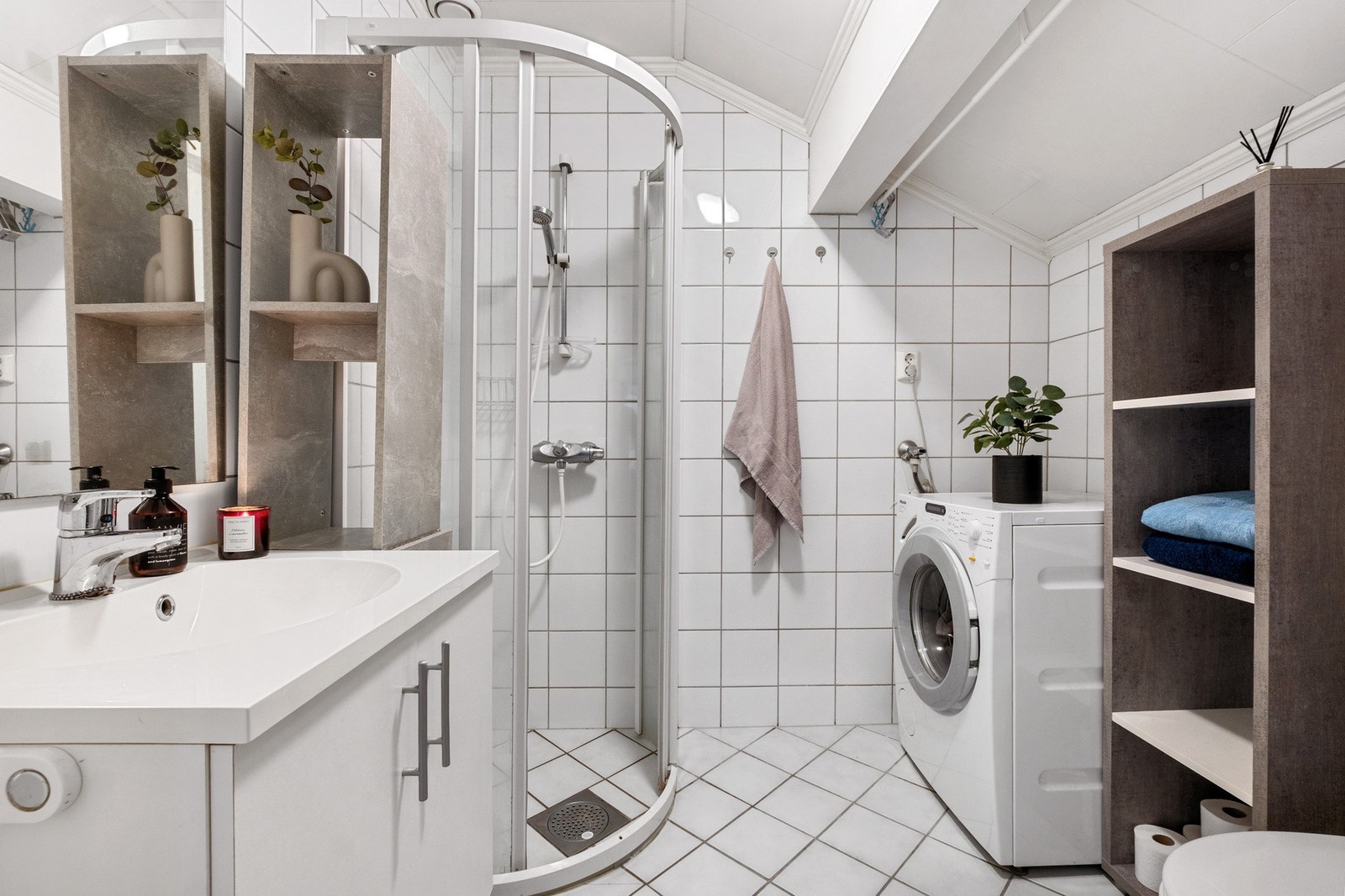 Flislagt bad med varmekabler på gulv. Dusjnisje med skyvedører, og servant med speil og underskap. Galleribilde