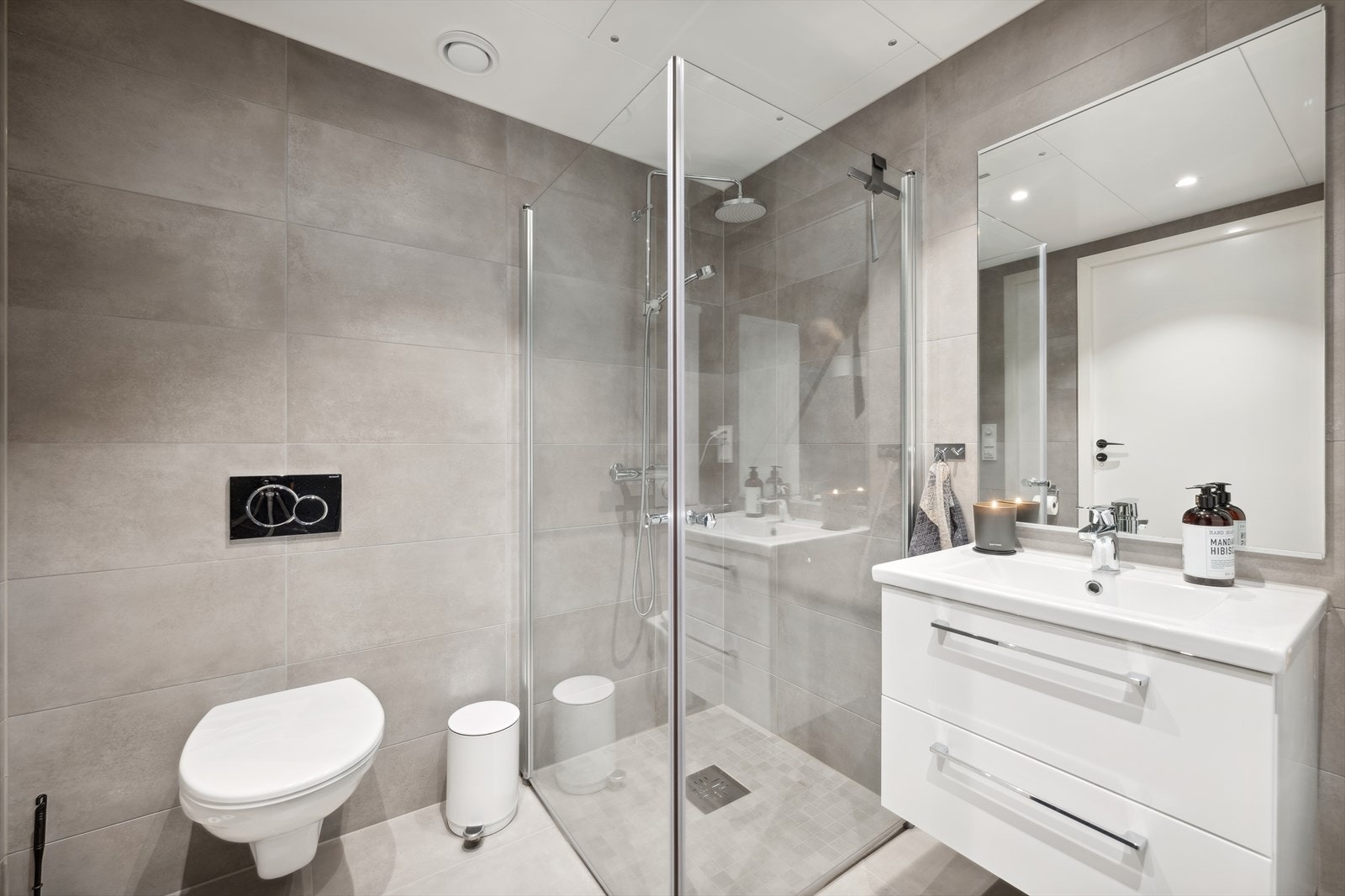 Lekkert flislagt bad med dusjnisje, vegghengt wc, innredning med servant og opplegg for vaskemaskin. Galleribilde