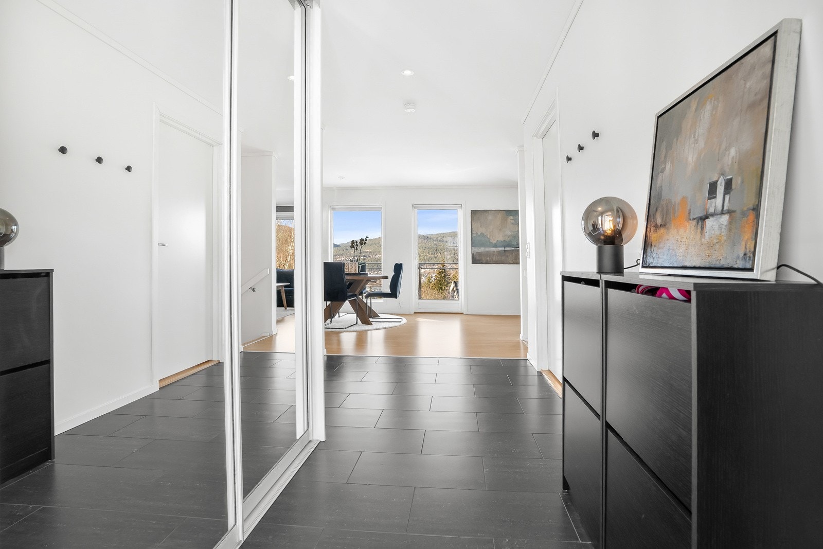 Romslig entré med flislagt gulv og skyvedørsgarderobe. Galleribilde