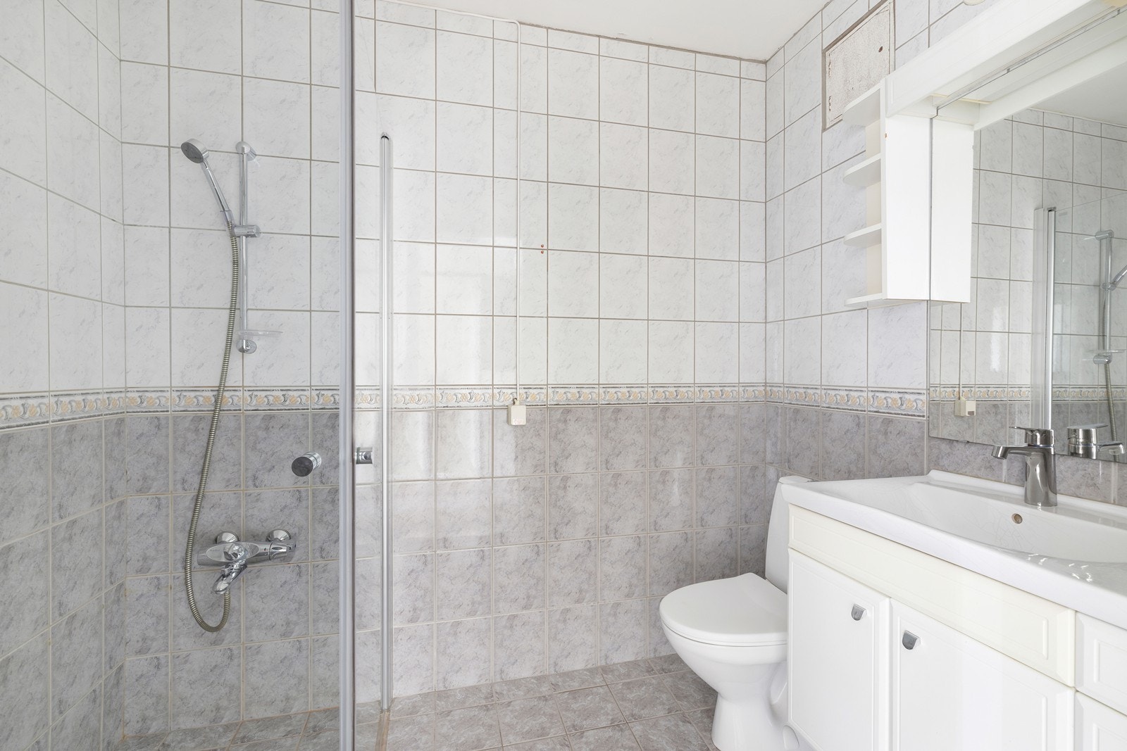 Flislagt bad som inneholder dusjhjørne, servant og wc Galleribilde