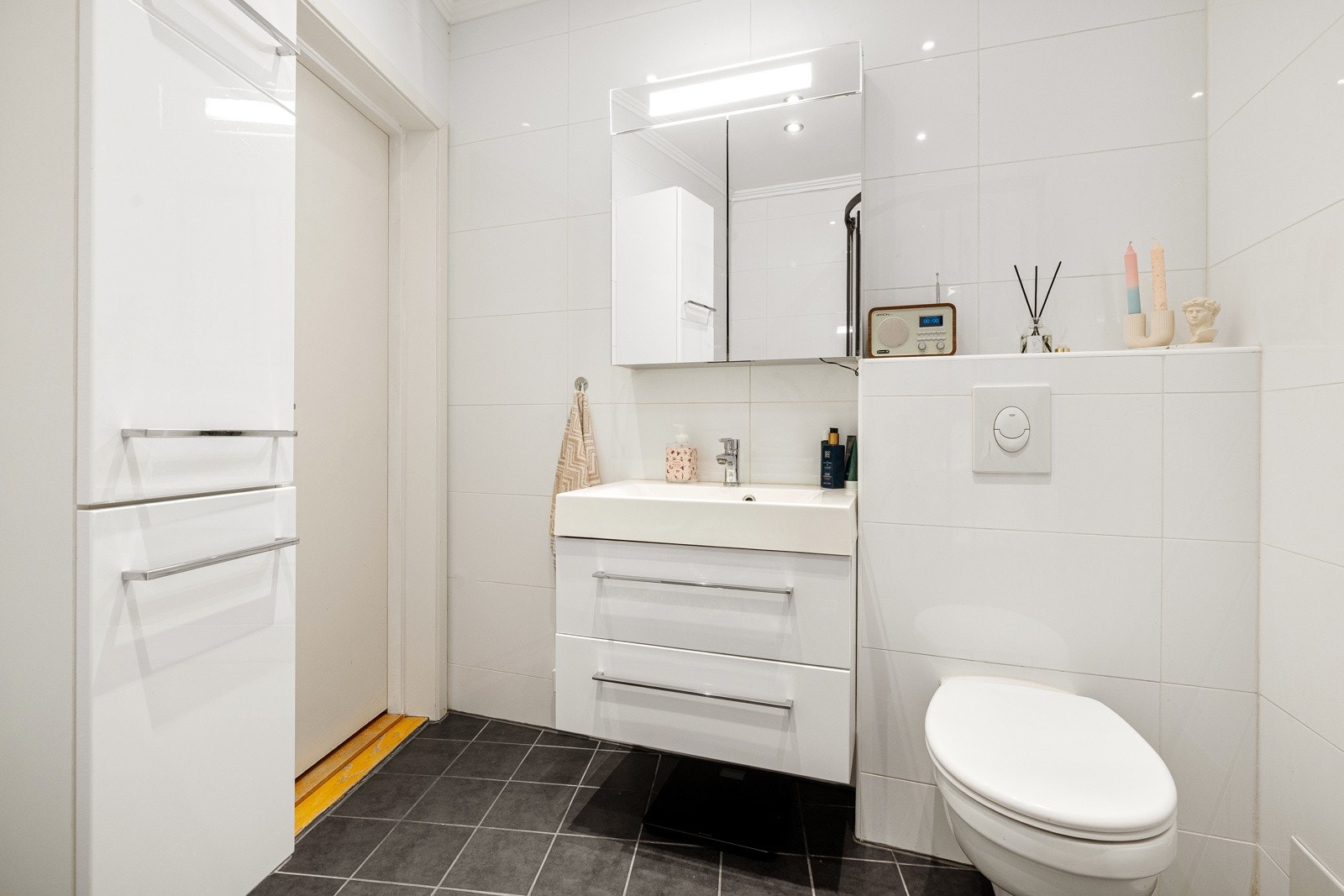 Speilskap med overlys og stikkontakt på vegg. Badet har også opplegg for vaskemaskin. Galleribilde