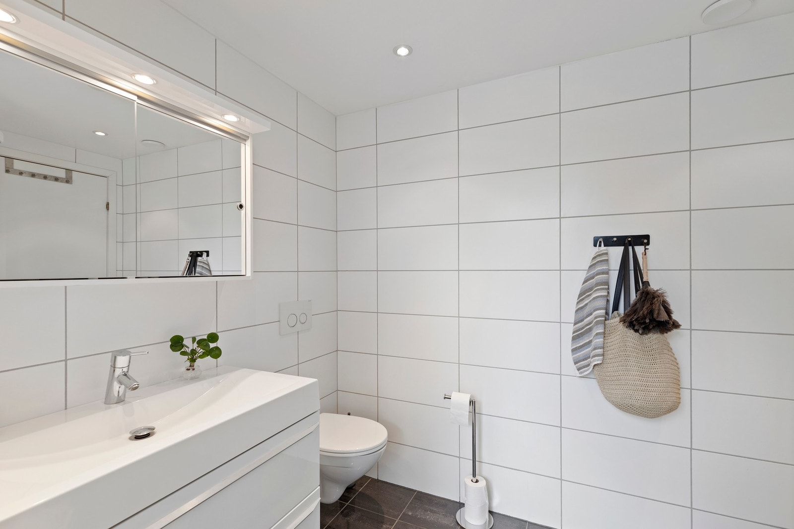 Pent, helfliset bad som inneholder baderomsinnredning med servant, dusjkabinett og vegghengt toalett. Galleribilde