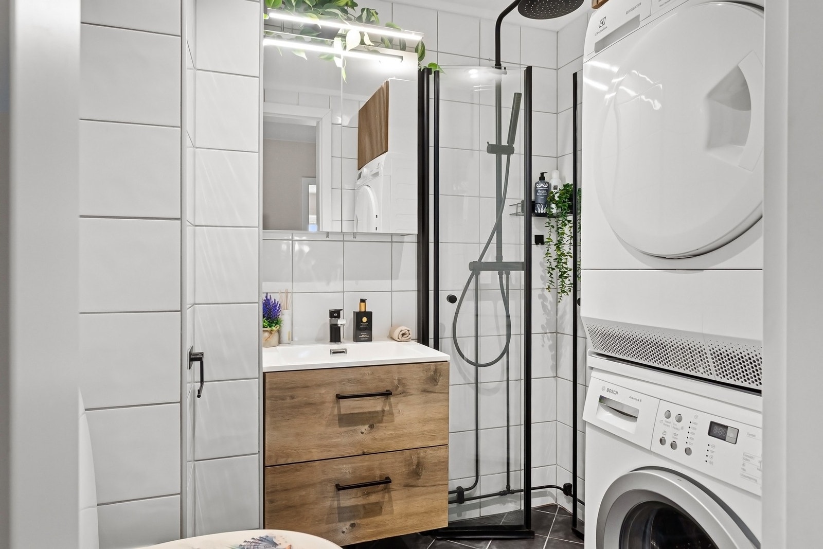 Ny servant med servantskap og blandebatteri, nytt speilskap, nye dusjdører, nytt dusjbatteri og dusjgarnityr samt nytt skap over tørketrommel i 2023. Galleribilde