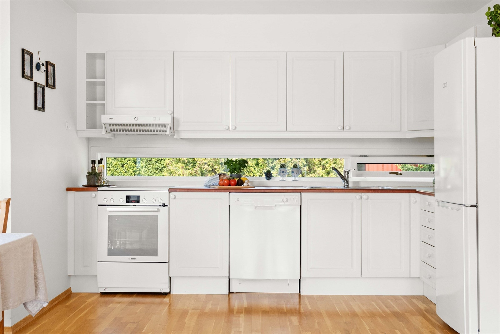 Kjøkkeninnredning med hvite profilerte fronter. Benkeplate av laminat samt nedfelt oppvaskkum med ett-greps
armatur. Galleribilde