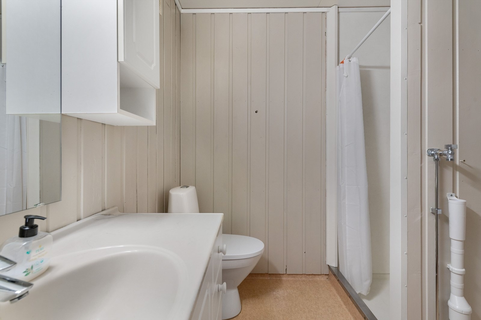 Baderommet er utstyrt med baderomsinnredning, dusjhjørne med forheng, gulvstående toalett og opplegg for vaskemaskin. Galleribilde