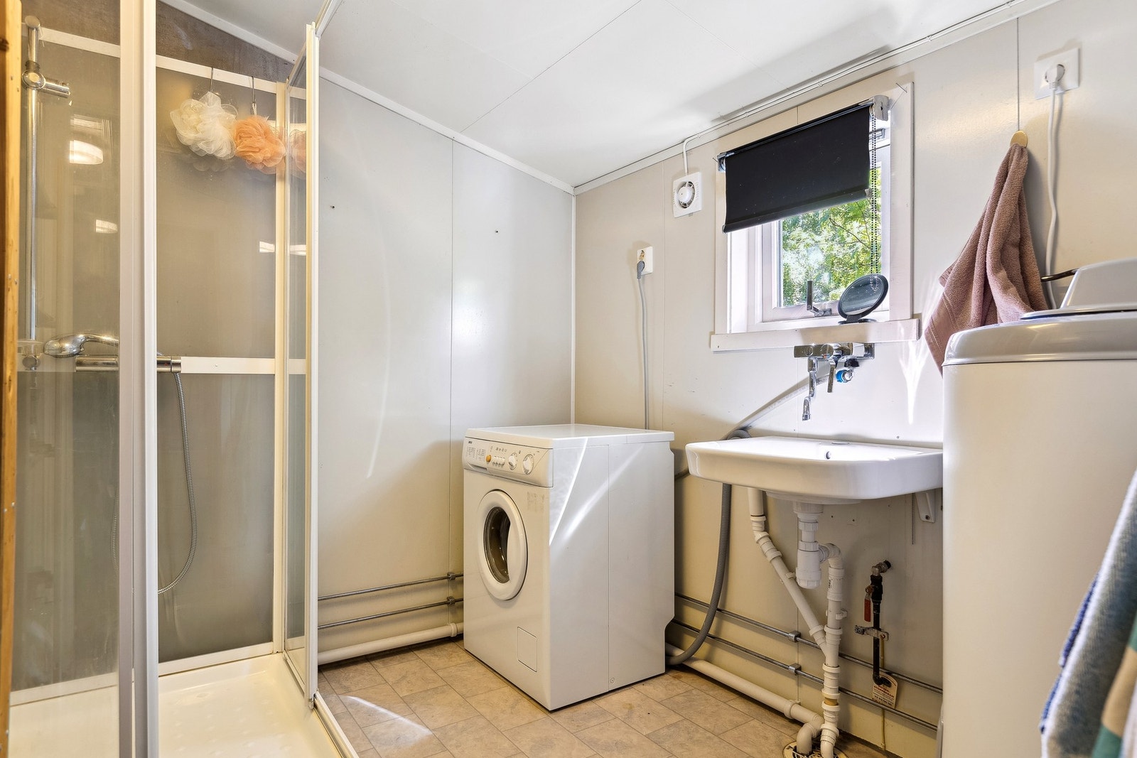 Baderommet har flislagte gulv og vegger, og er innredet med dusjkabinett og servant, og har en praktisk og funksjonell utforming. Galleribilde