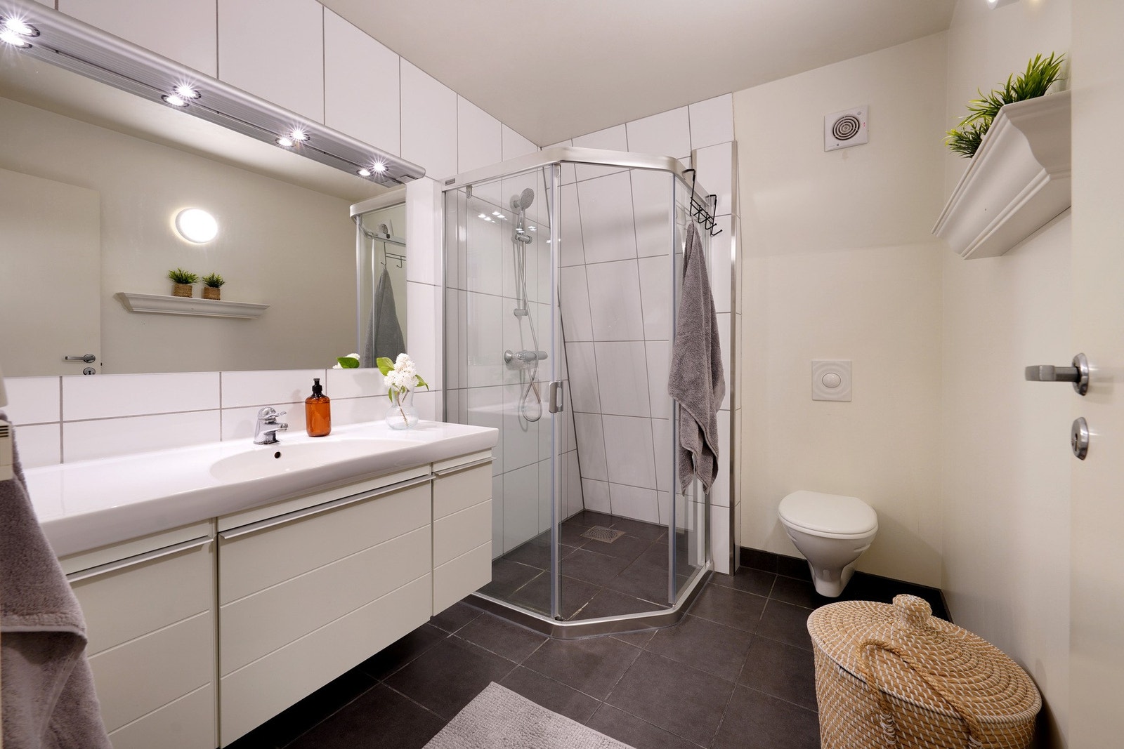 Bad med fliselagt gulv og gulvarme. Dusjnisje og veggehengt servant Galleribilde