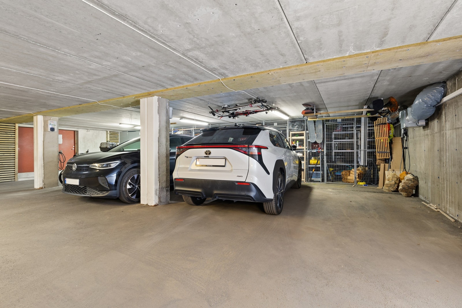 Her medfølger det to garasjeplasser, hvorav én er utstyrt med elbillader. Hvit bil markerer plass tilhørende bolig. Galleribilde