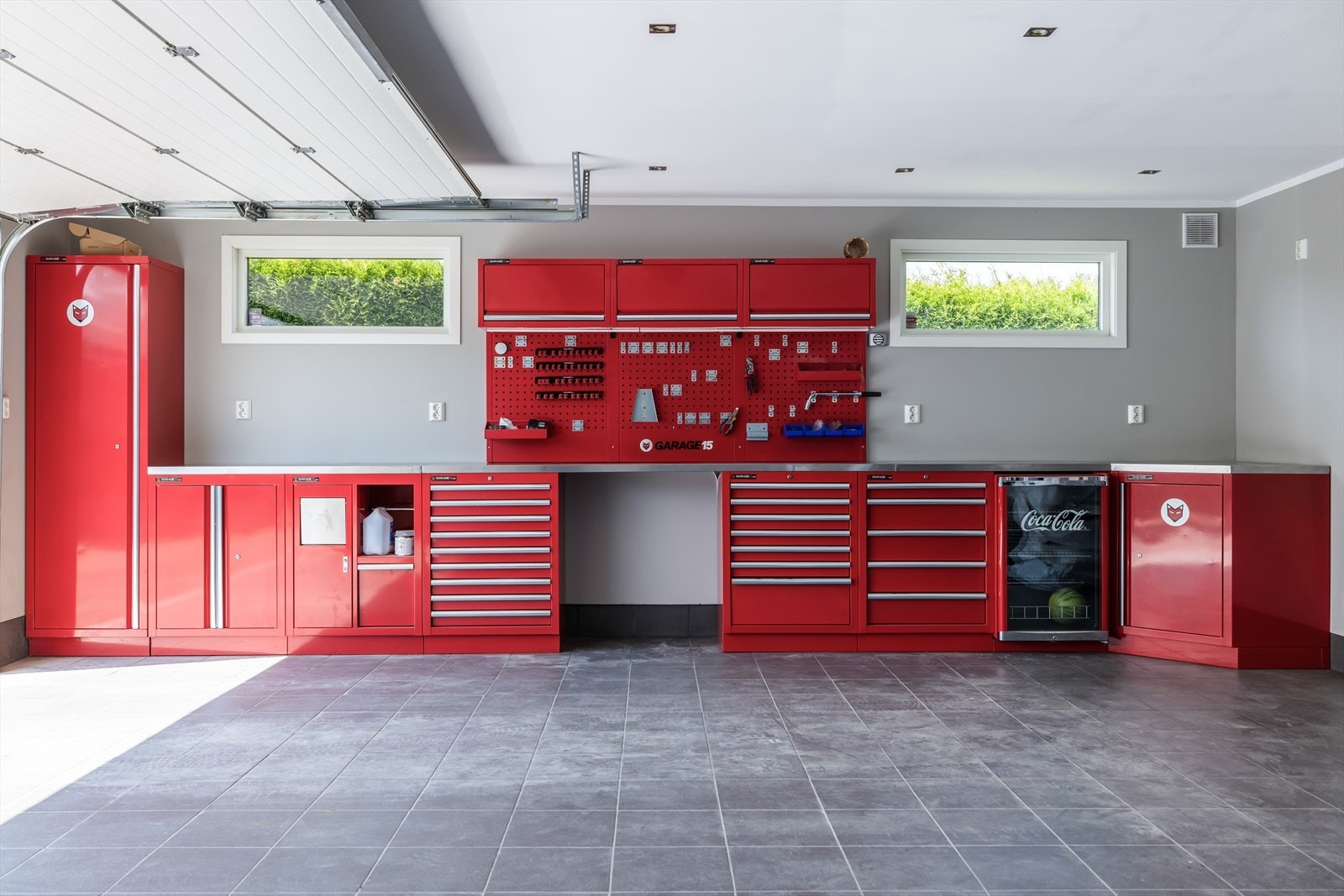 I garasjen er det fliser på gulv, malte plater på vegger og malte plater i tak med LED spotter. Galleribilde