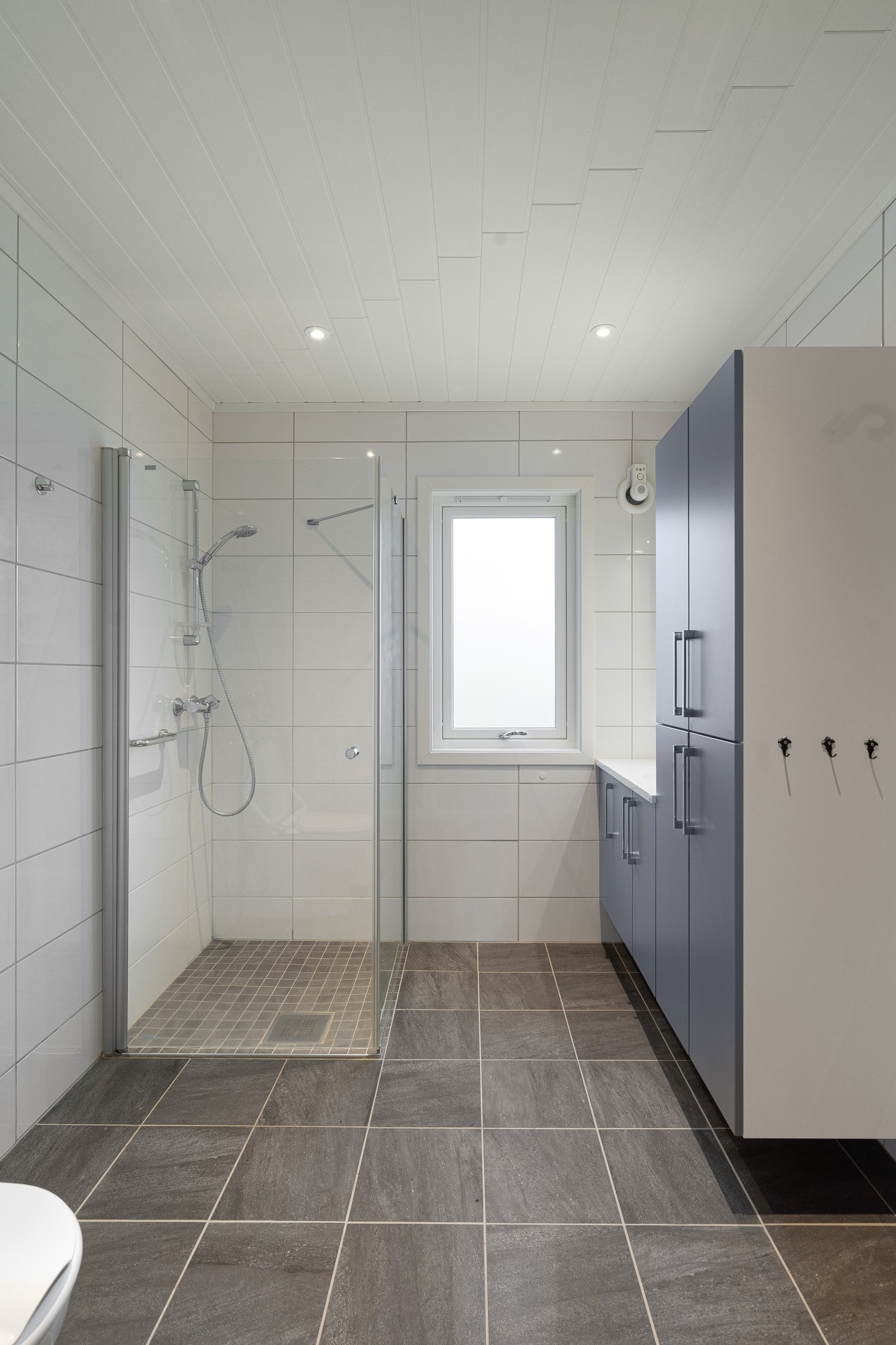 Pent baderom med flislagt gulv og downlights i himling. Galleribilde