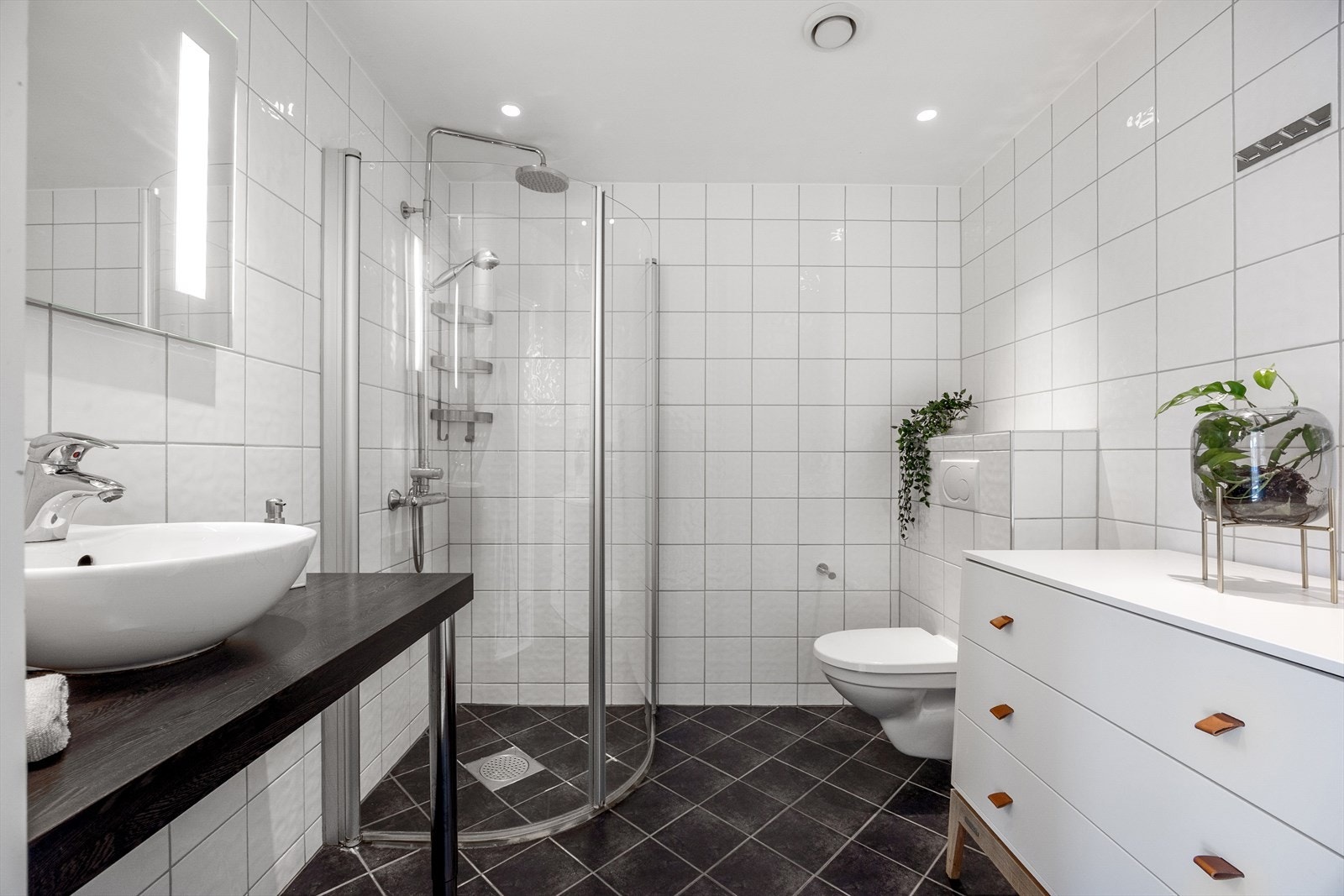 Badet er innredet med vegghengt WC, dusjhjørne, servant, speil med lys og spotter i himling. Galleribilde