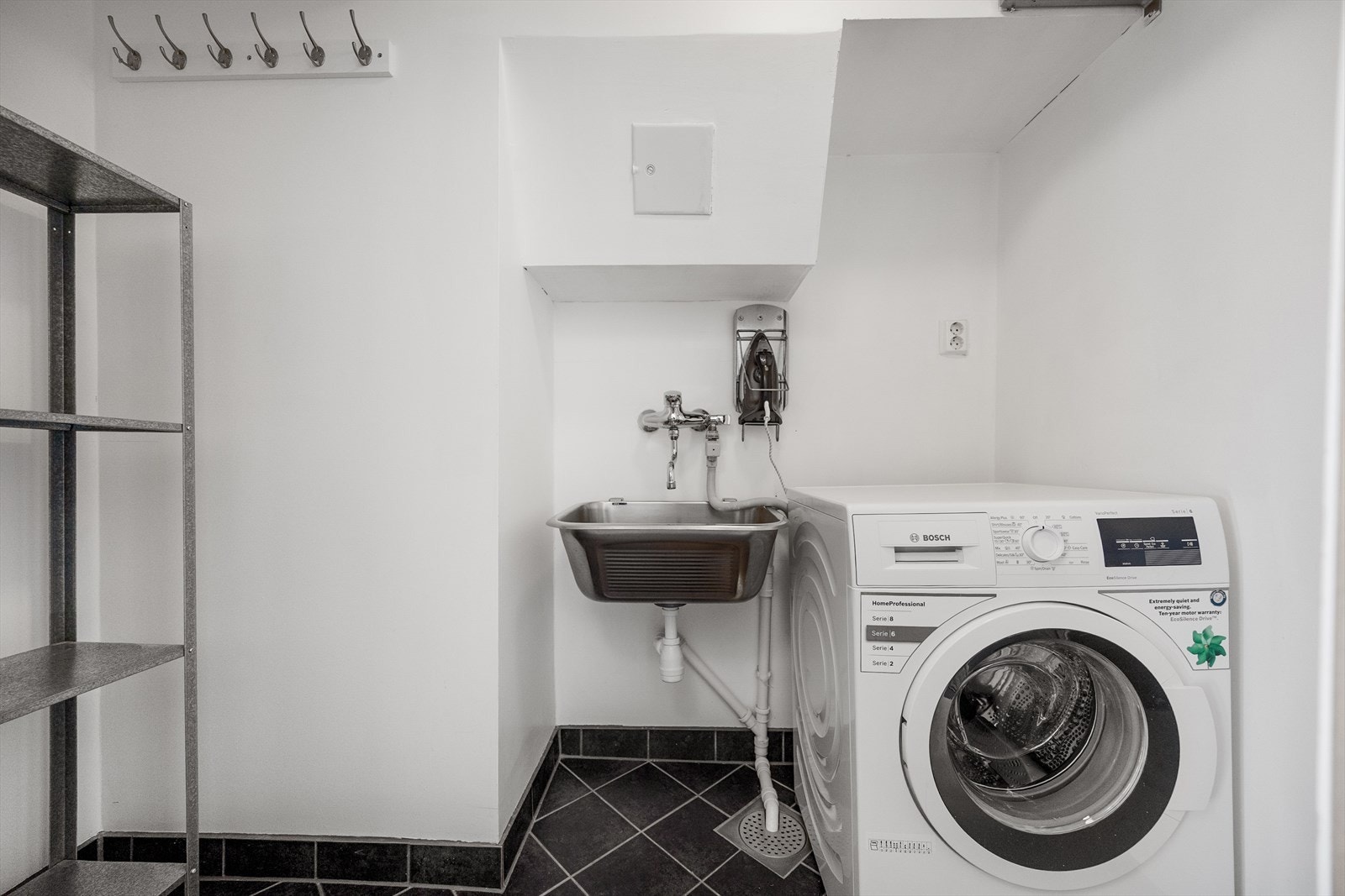 I tilknytning til entréen har også leiligheten flislagt vaskerom innredet med utslagsvask og opplegg for vaskemaskin. Galleribilde