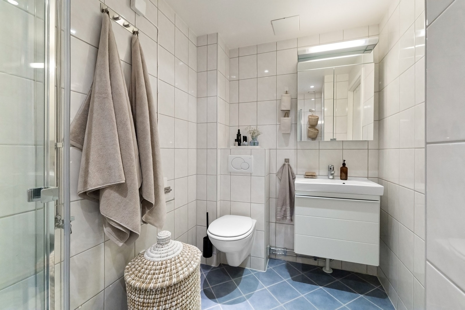 Et pent, flislagt bad med varmekabler, downlights i himling og opplegg for vaskemaskin Galleribilde