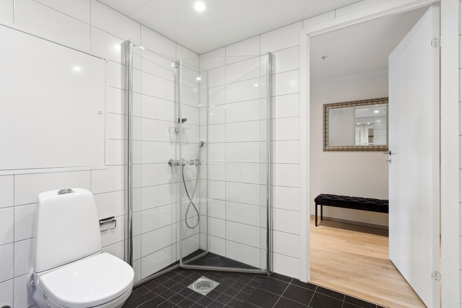 Badet er utstyrt med servant med underskap, benkeplate, overskap med speilfronter og overlys, samt veggmontert klosett. Galleribilde