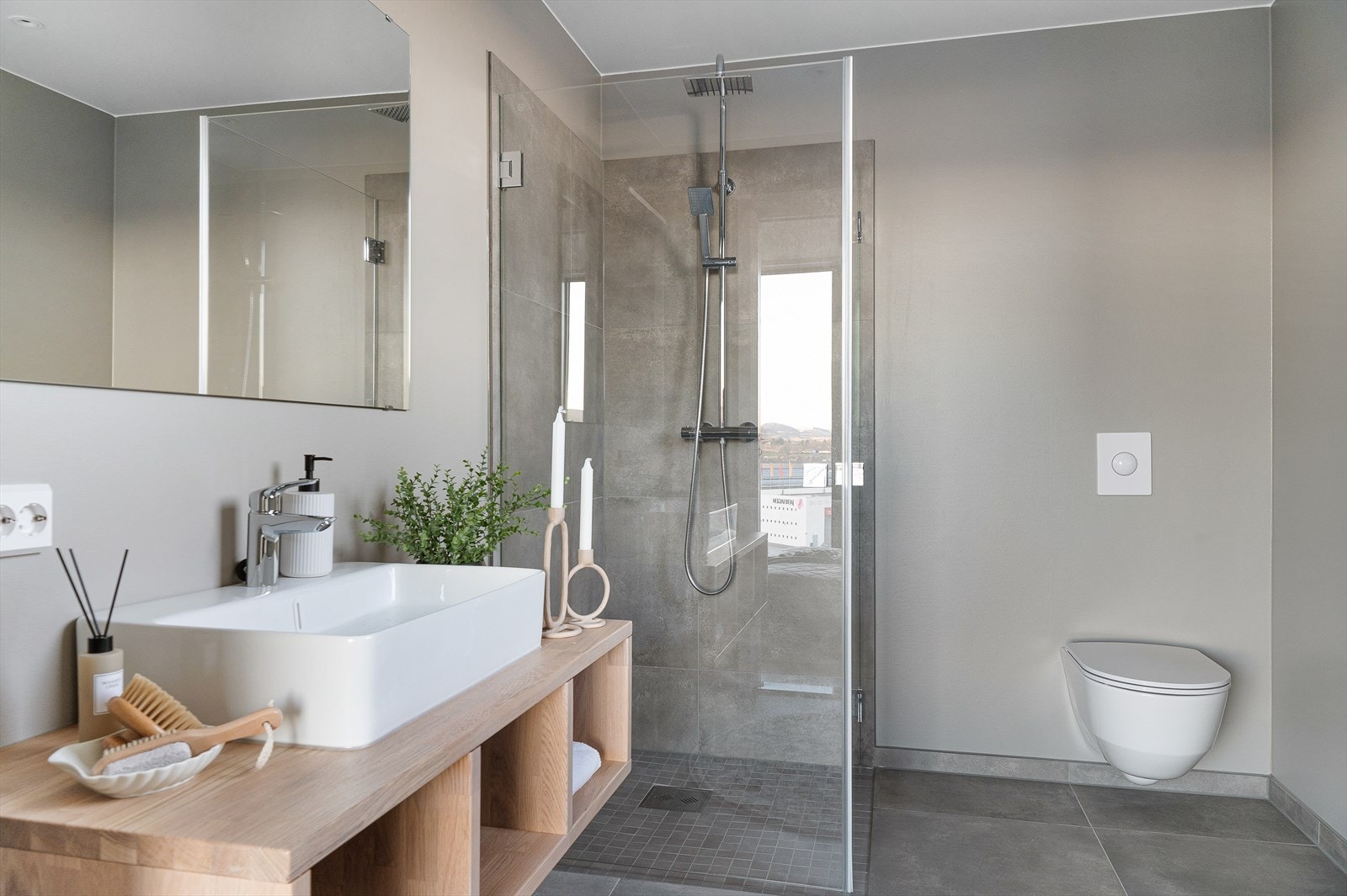 Badet inneholder servant med oppbevaringsplass, speil, dusj og vegghengt toalett Galleribilde