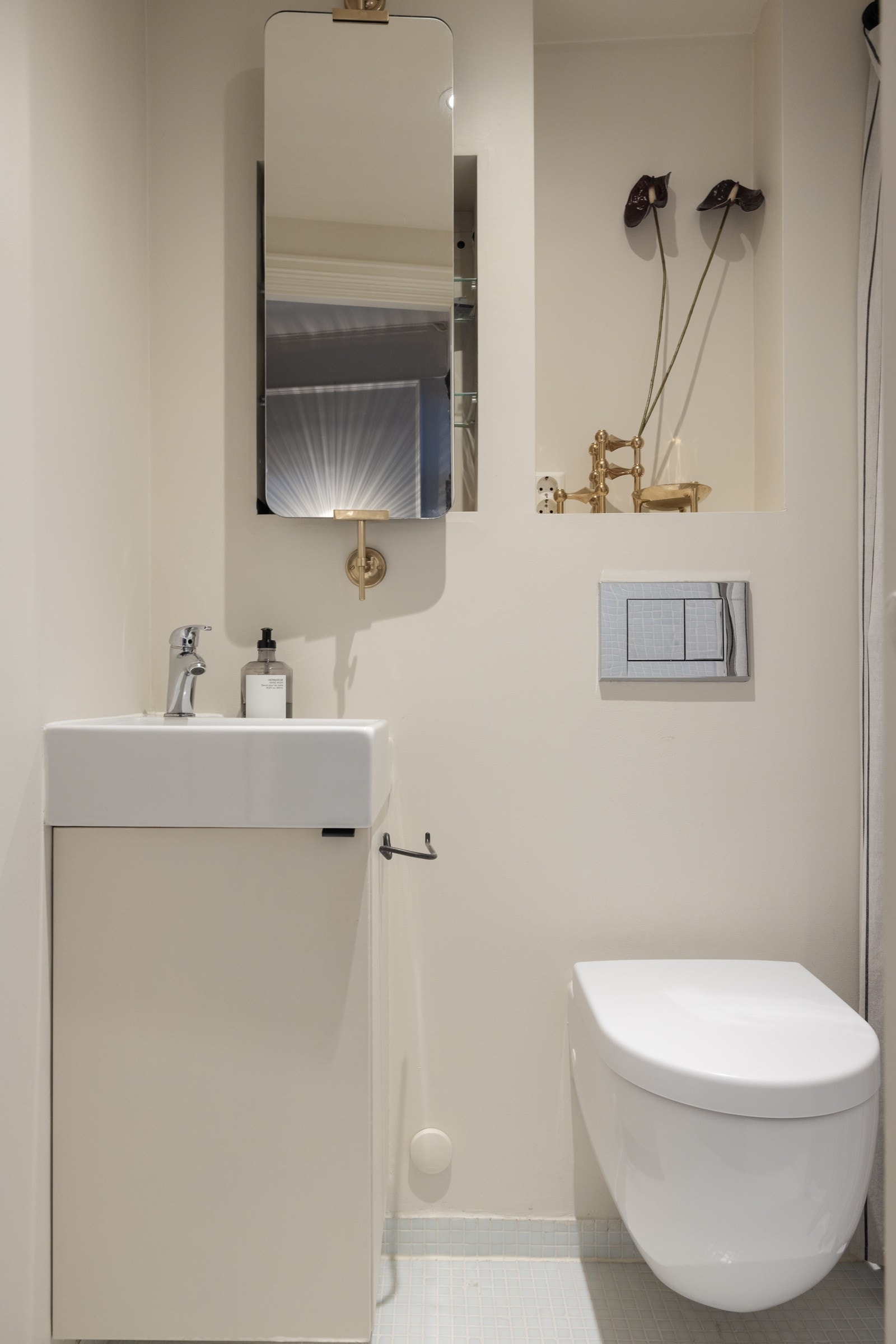 Pent flislagt baderom fra 2013 med vegghengt toalett, pen baderomsinnredning og tilhørende speil som står i stil med resten av rommet. Galleribilde