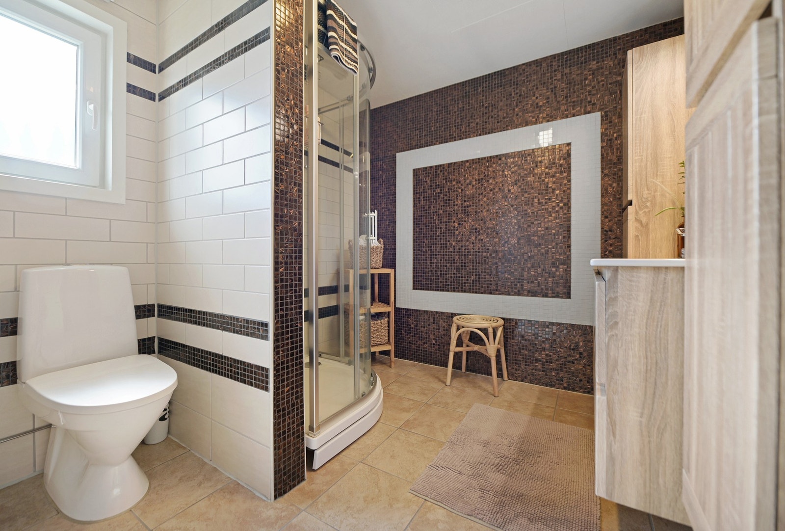 Hovedbadet er innredet med gulvfestet toalett , nedfelt servant og dusjkabinett Galleribilde