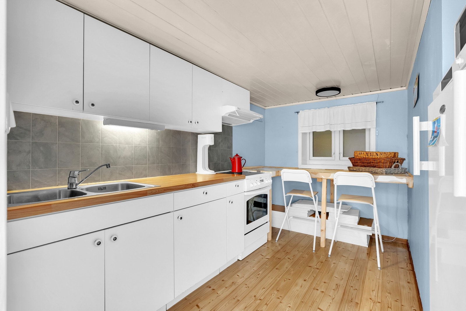 Kjøkkenet i underetasjen har en tilsvarende løsning med folierte skrog, glatte fronter og en foliert topplate med vask. Galleribilde