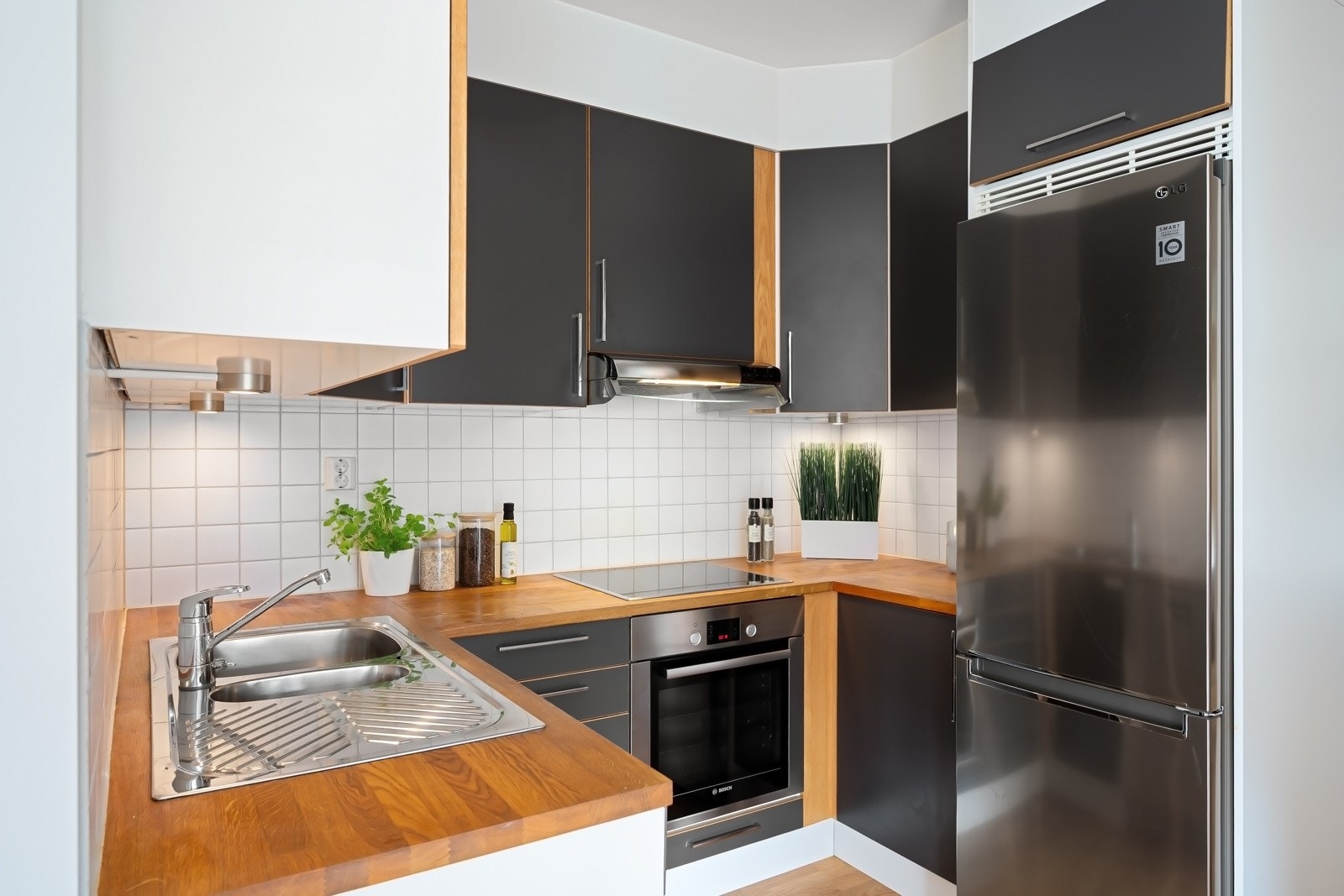 Kjøkkeninnredning har glatte fronter, benkeplate av heltre og oppvaskkum av stål Galleribilde