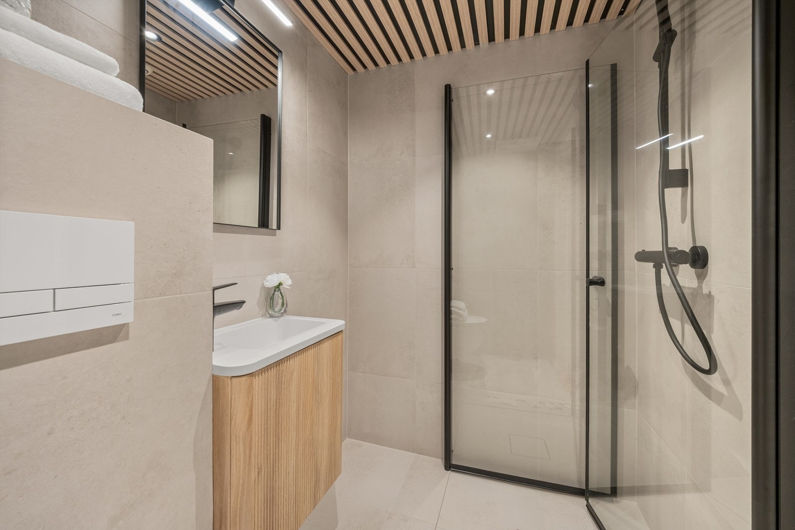 Badet er utstyrt med servant med skap, speil med lys, toalett og dusjnisje med regndusj og innfellbare glassdører. Galleribilde